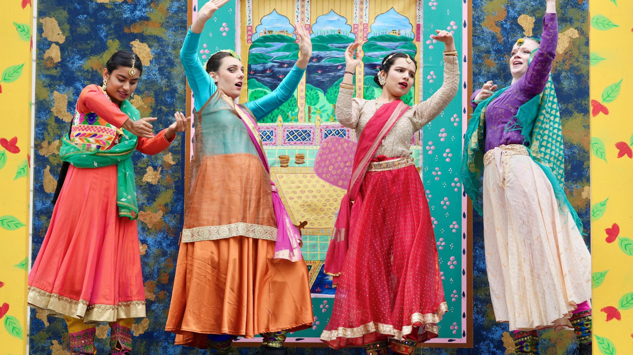 A dance group posing in brightly coloured costumes