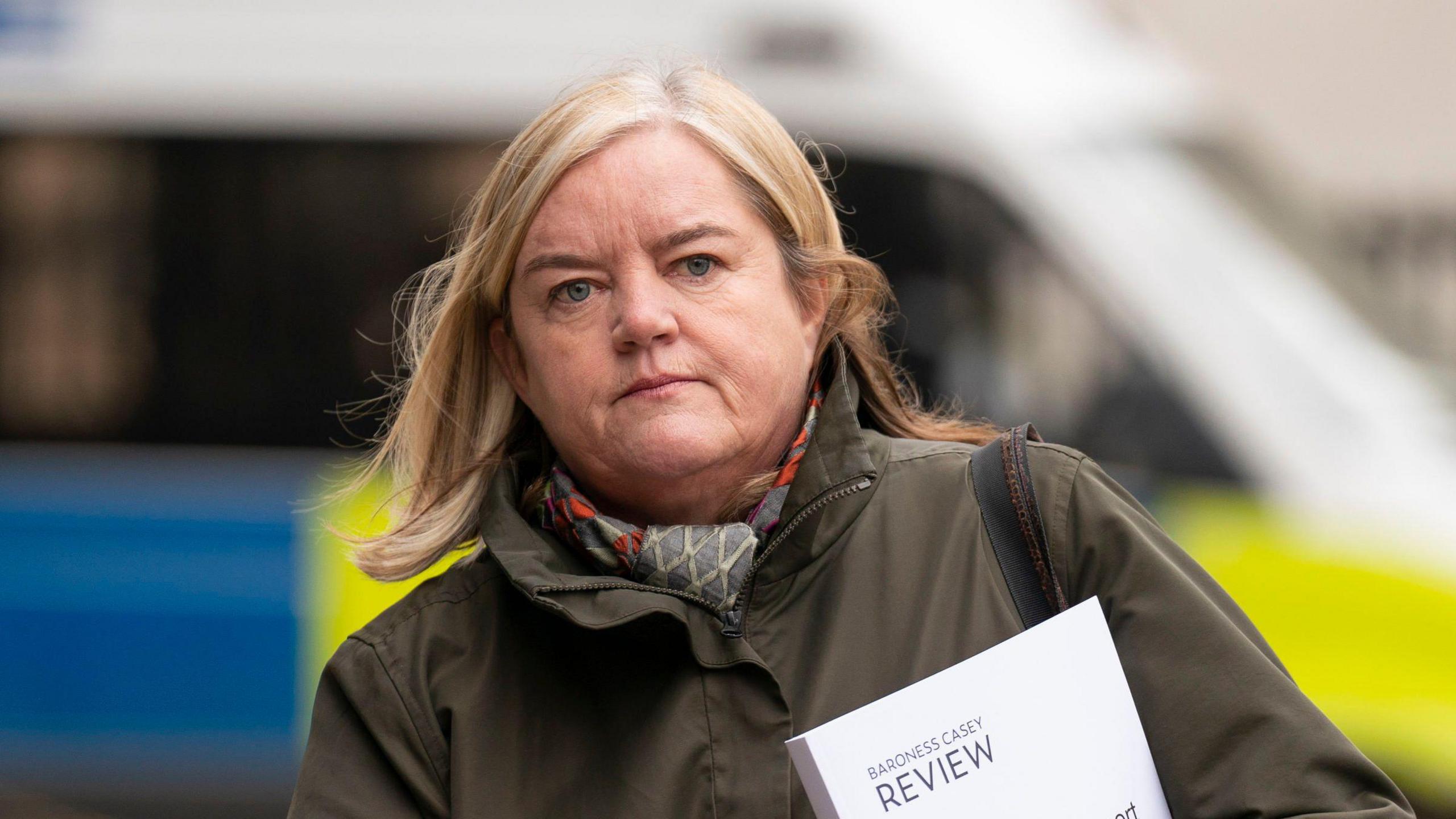 Image from 2023 of Baroness Louise Casey holding a copy of her previous review into police culture as she walks to a conference. She is wearing a dark coat and scarf