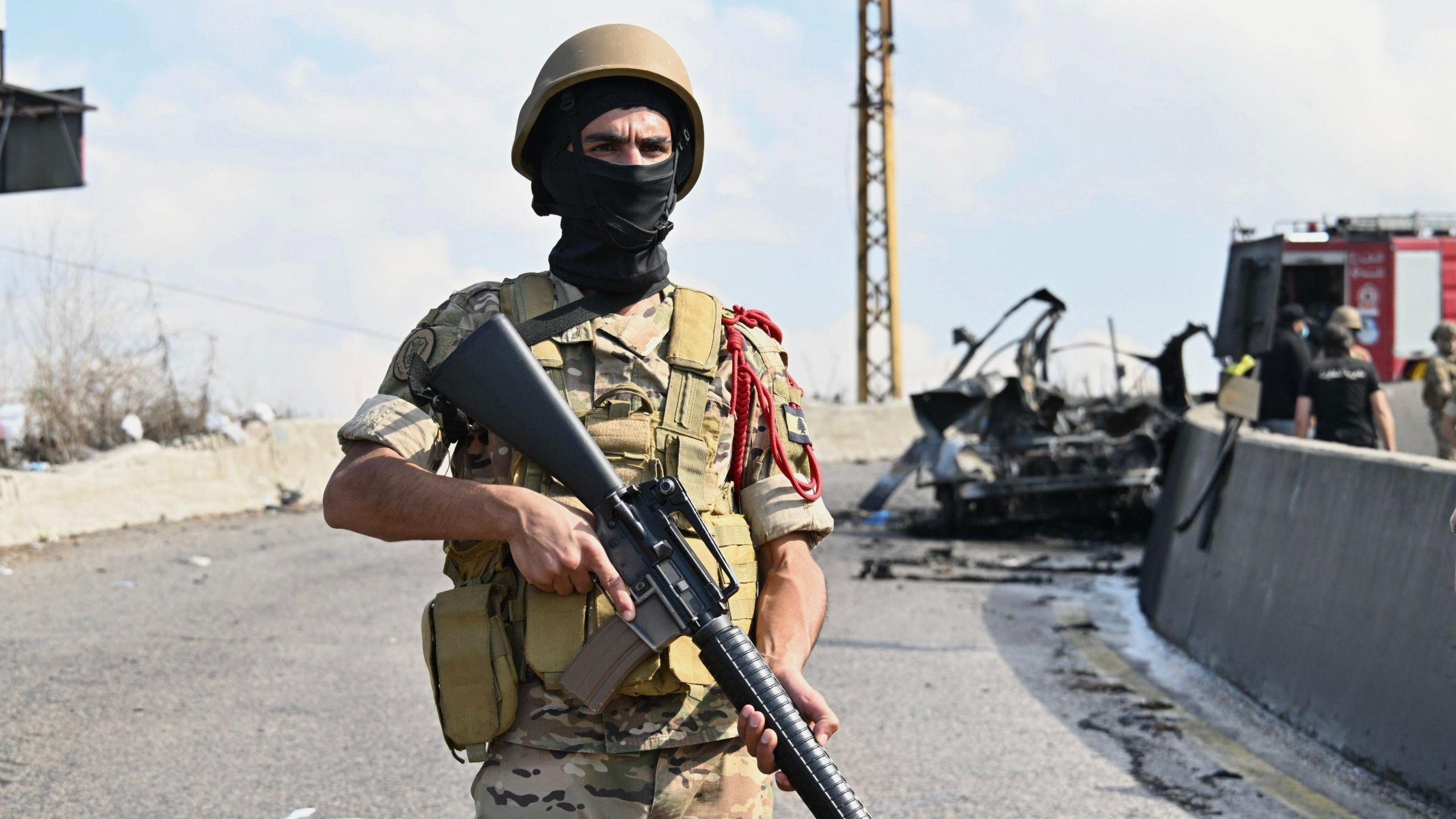 A Lebanese soldier stands in front of the wreckage of a car