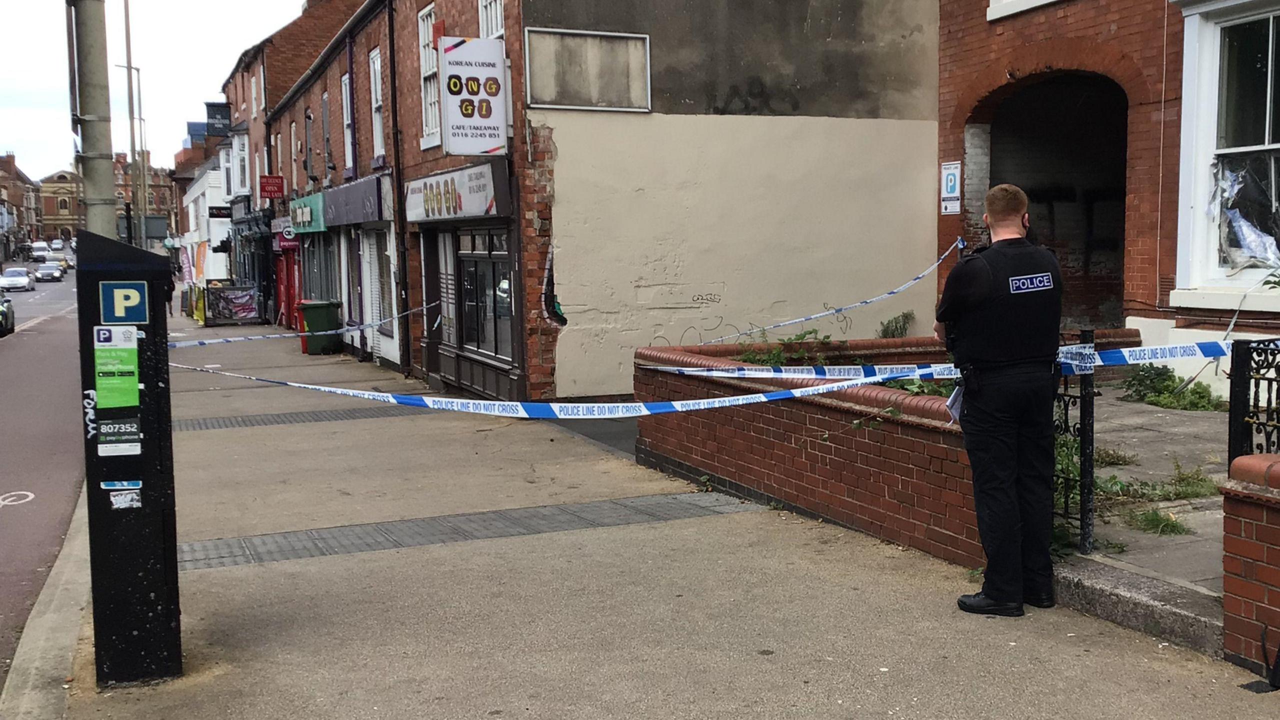 An officer standing on a cordon outside a property on a main road