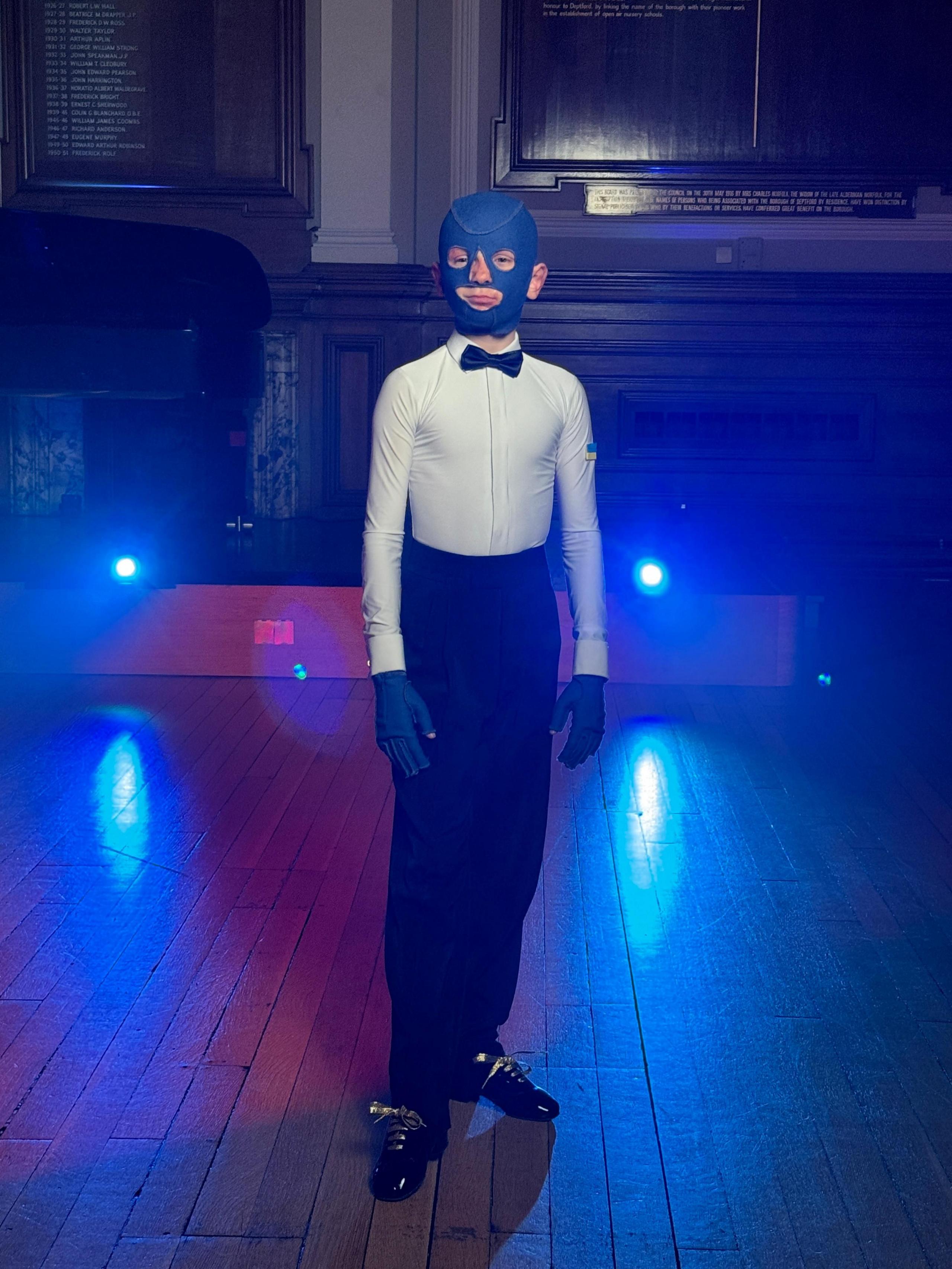 The actor playing  Roman Oleksiv in white shirt, black shoes and trousers and blue gloves and mask