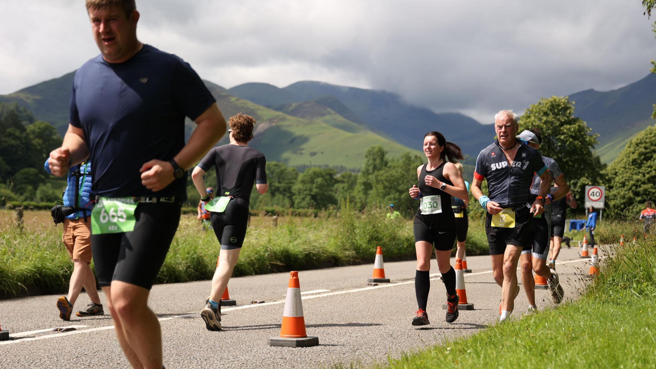 Los of people running with the Cumbrian Hills behind.