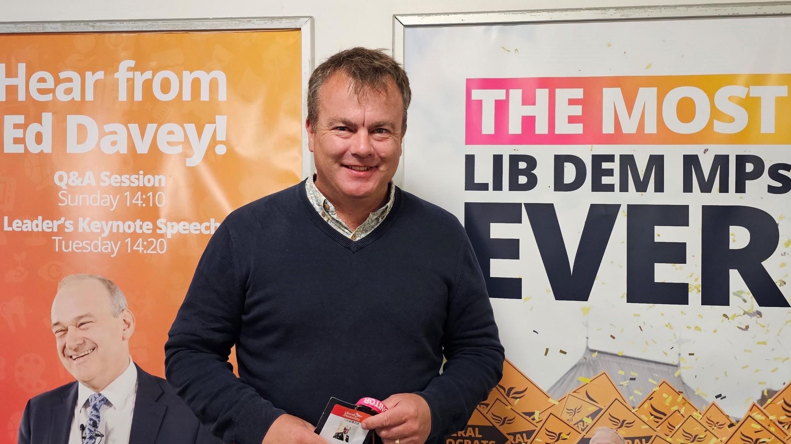 Lib Dem Kent county councillor Richard Streatfeild standing in front of two Lib Dem posters at the conference in Brighton