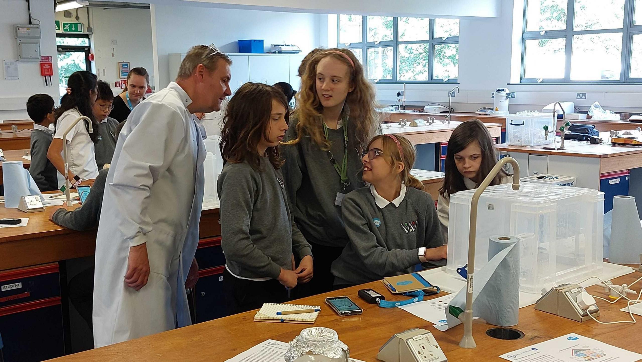 Four Students in a lab with a scientist doing laboratory experiments.