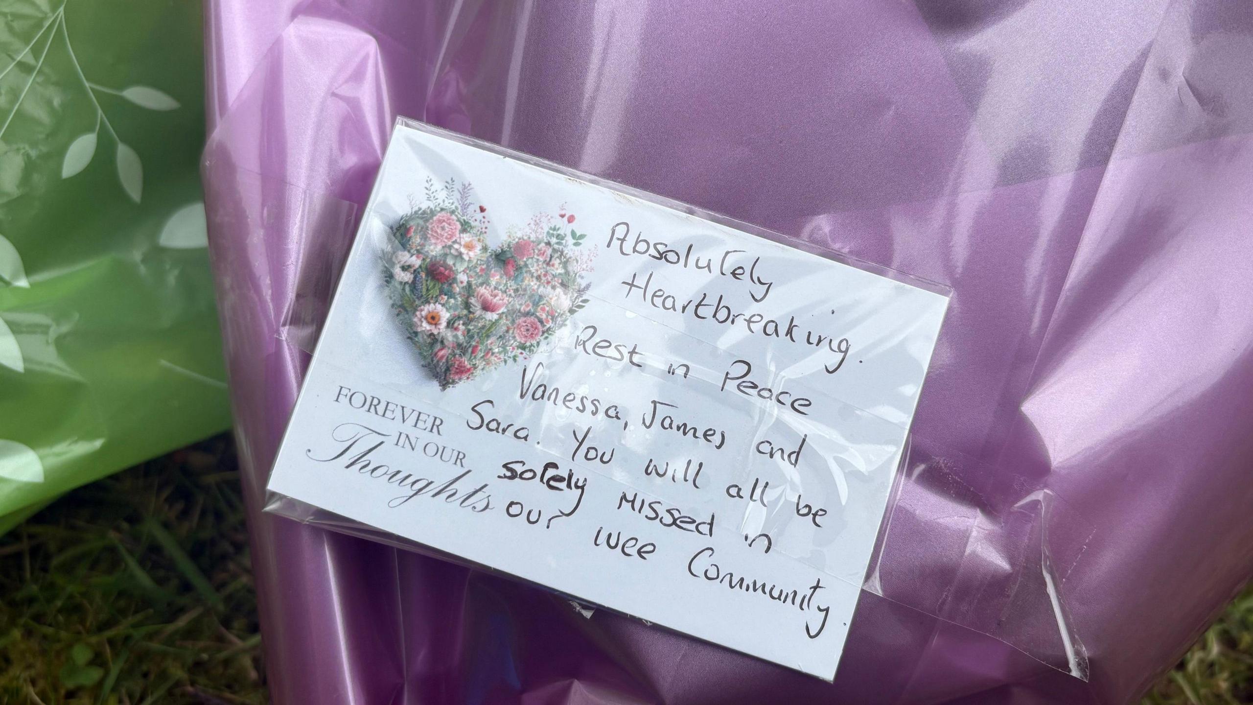 A close-up of a handwritten note on a bunch of flowers left near the murder scene. It reads: Absolutely heartbreaking. Rest in peace Vanessa, James and Sara. you will all be sorely missed in our wee community.