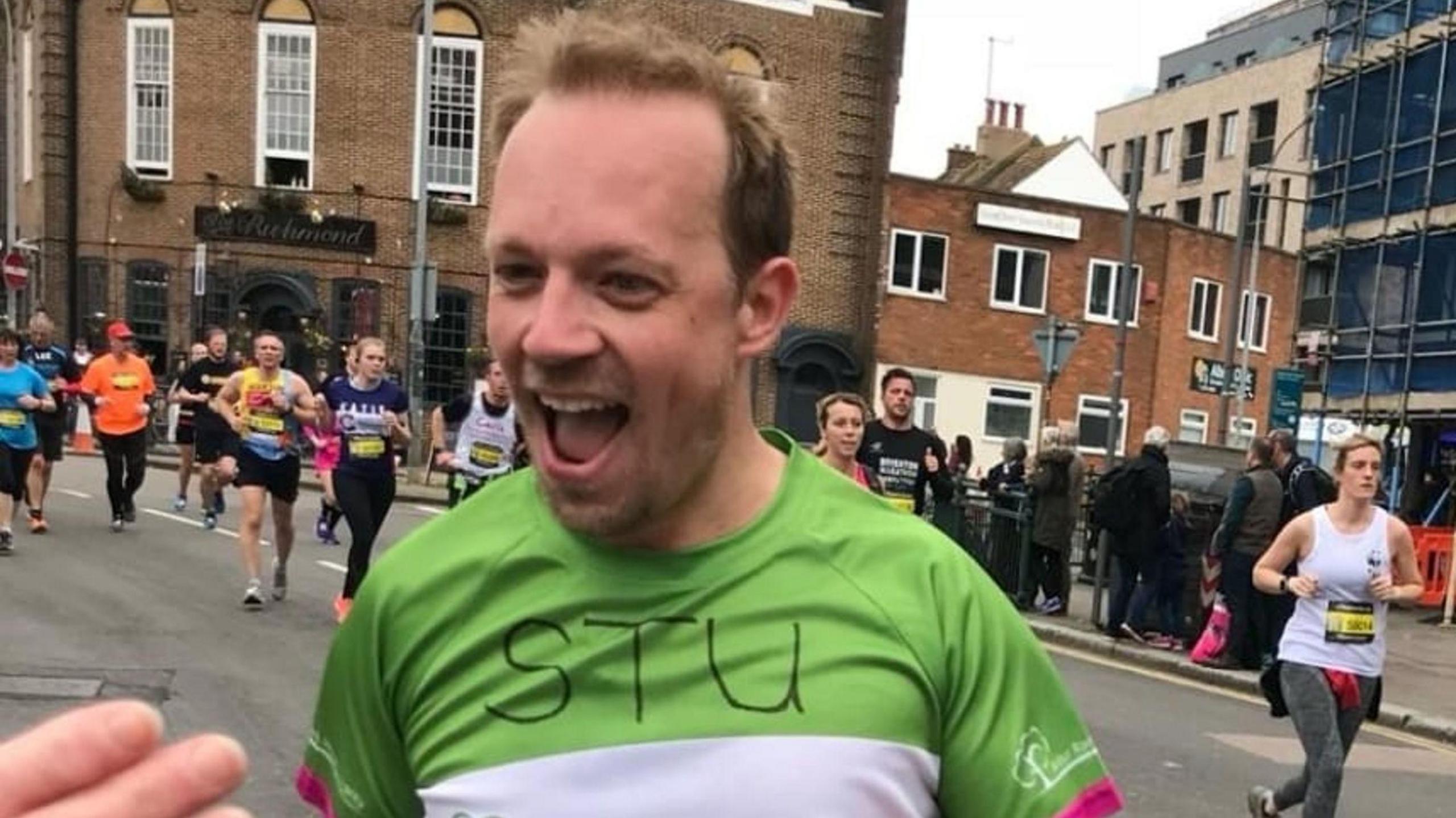 Stuart Elsom with short brown hair wearing a green and white top in a running race