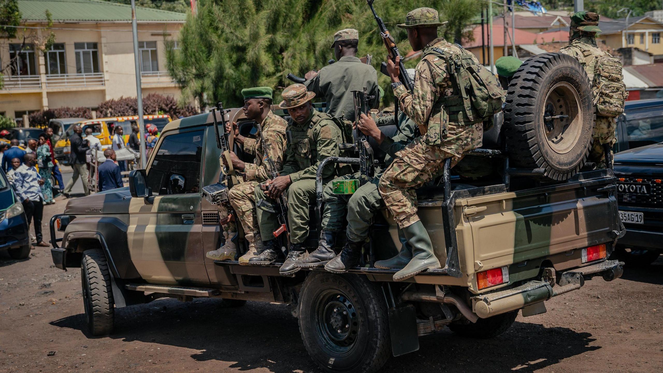 M23 rebel soldiers in camouflage and carrying guns ride on the back of a pick-up truck in Goma