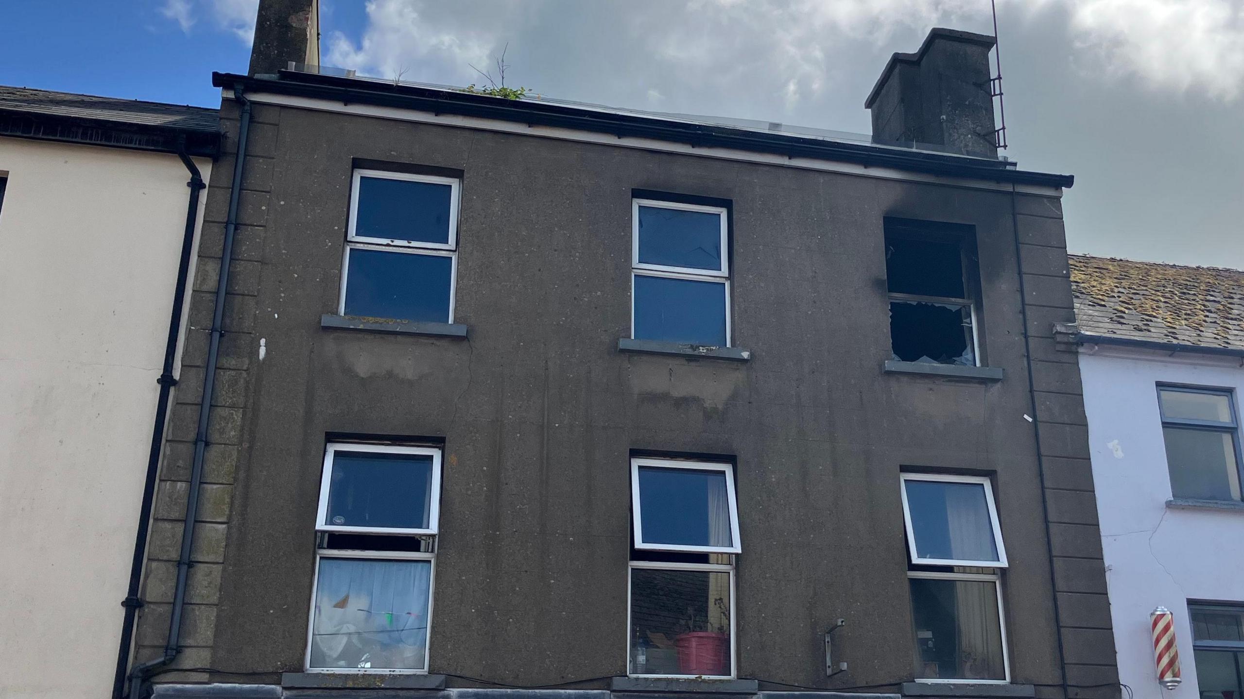 The picture shows a burnt-out brown-stone building with the glass missing one of the windows