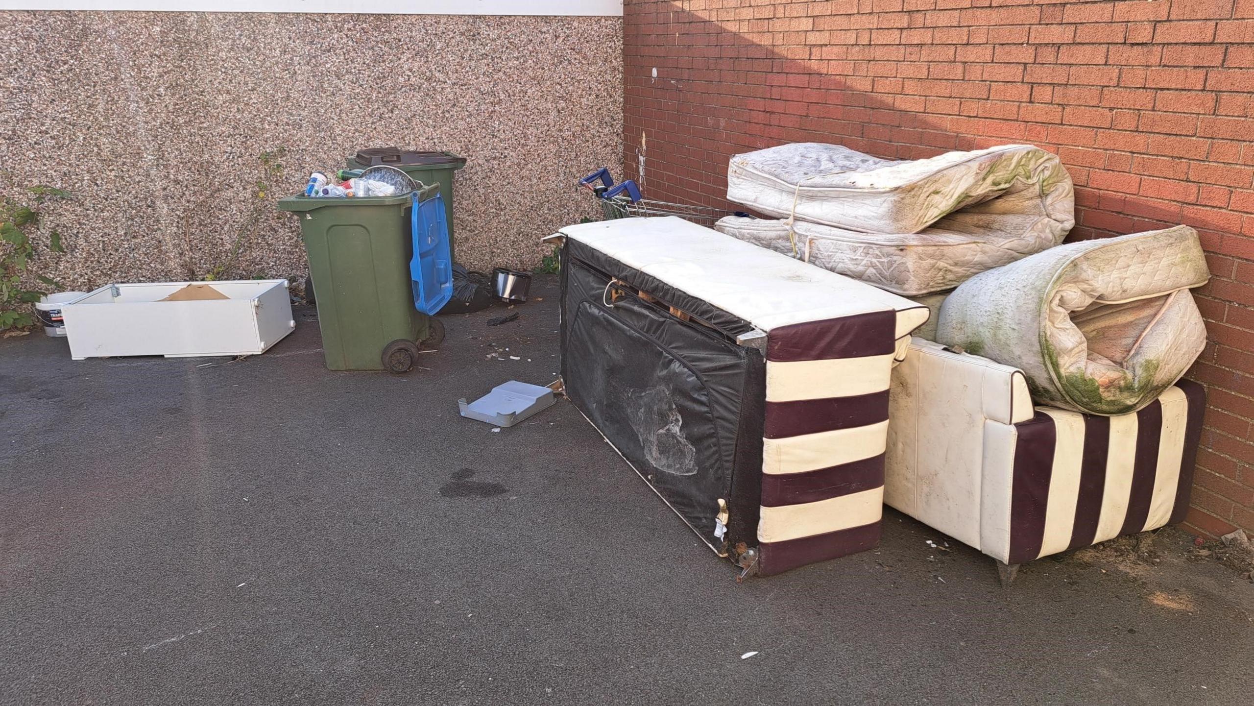 Mouldy mattresses and sofas next to green wheelie bins dumped at the top of Doncaster Close on the Manor Farm estate in Coventry 