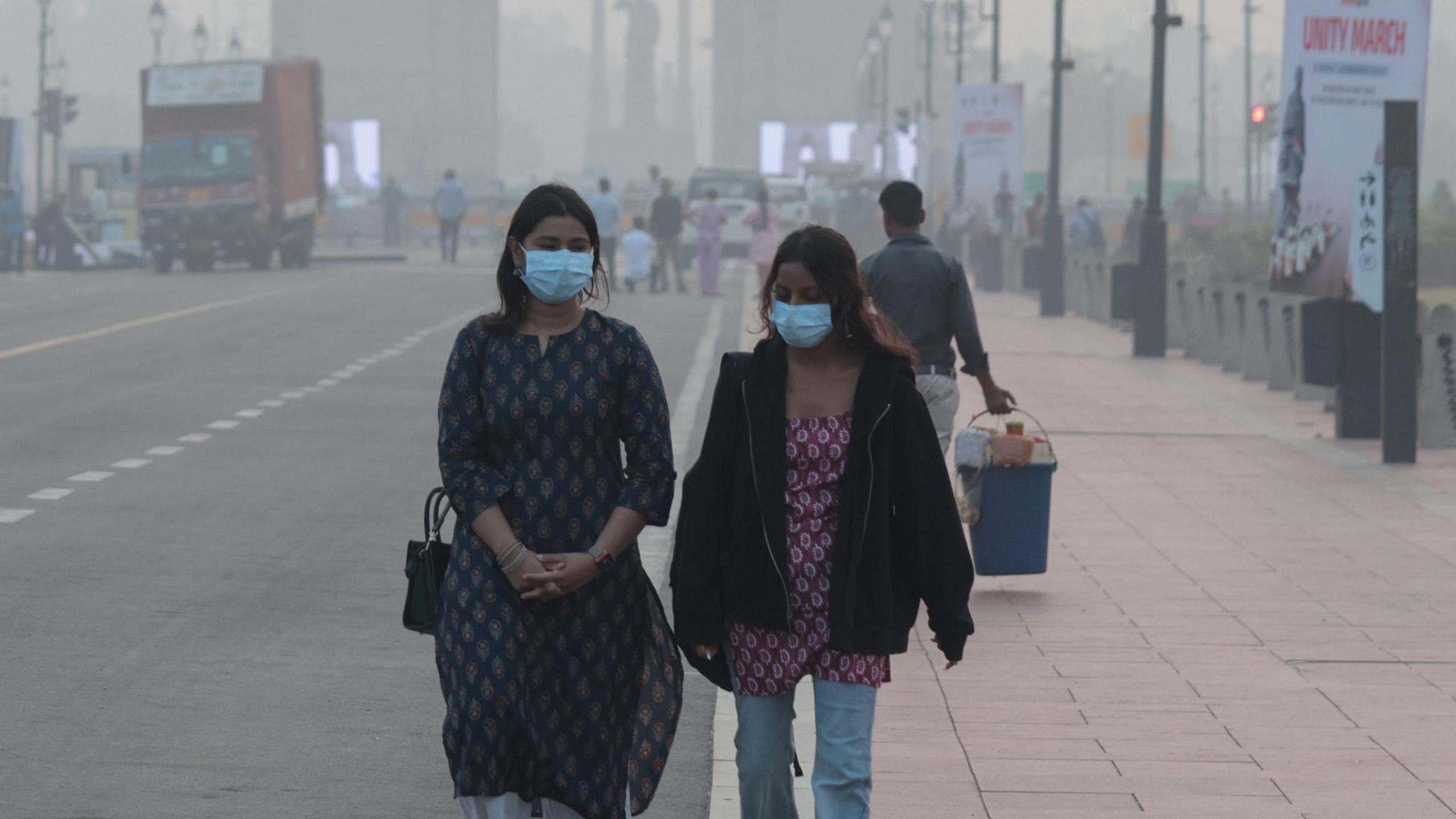 Indian girls wearing face masks walk amid heavy smog at Rajpath in New Delhi, India on 31 October, 2025.