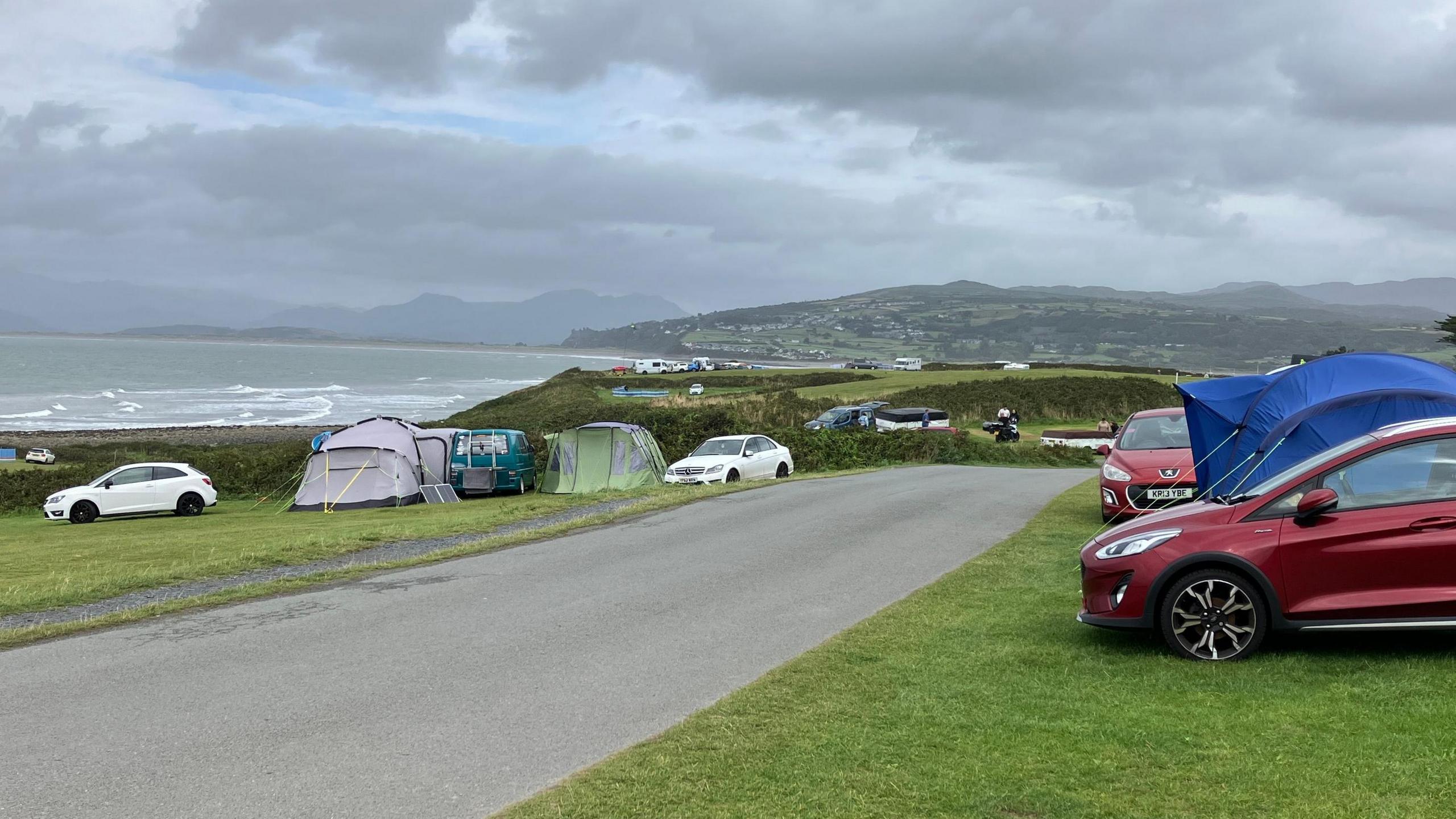 Cars parked on a field with tents put up beside them at Shell Island 