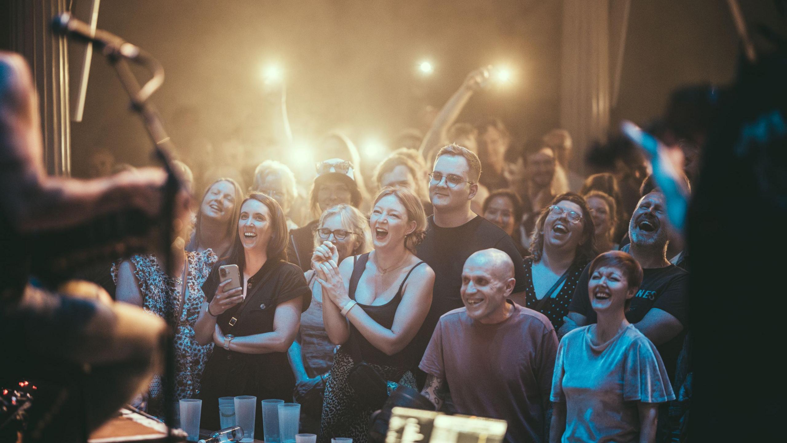 The people in the front row of St Georges in Bristol smile as they watch Talisk perform during the Bristol Folk Festival