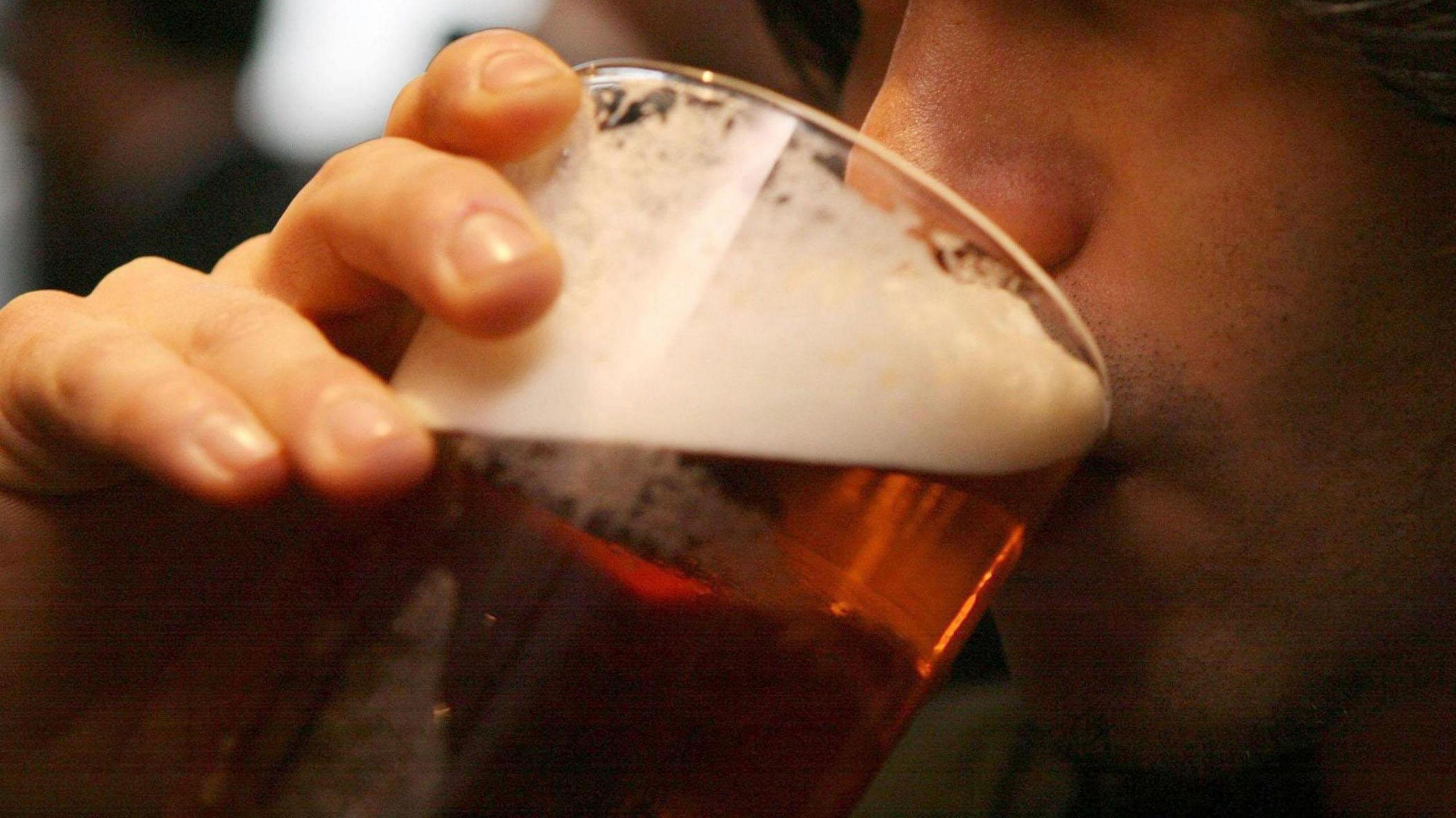 Person drinking pint of beer