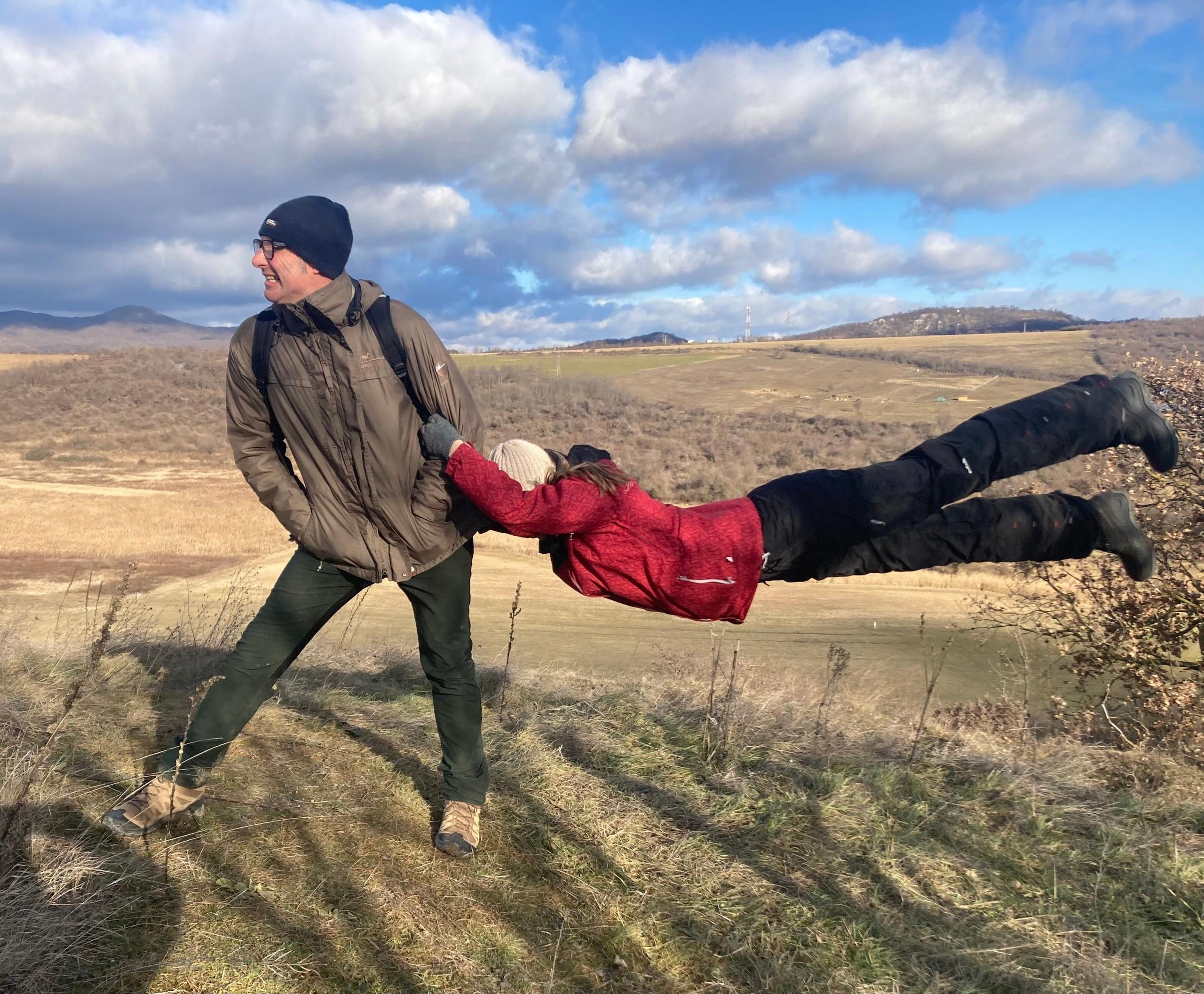 A posed picture of a woman holding on to a man as the wind blows