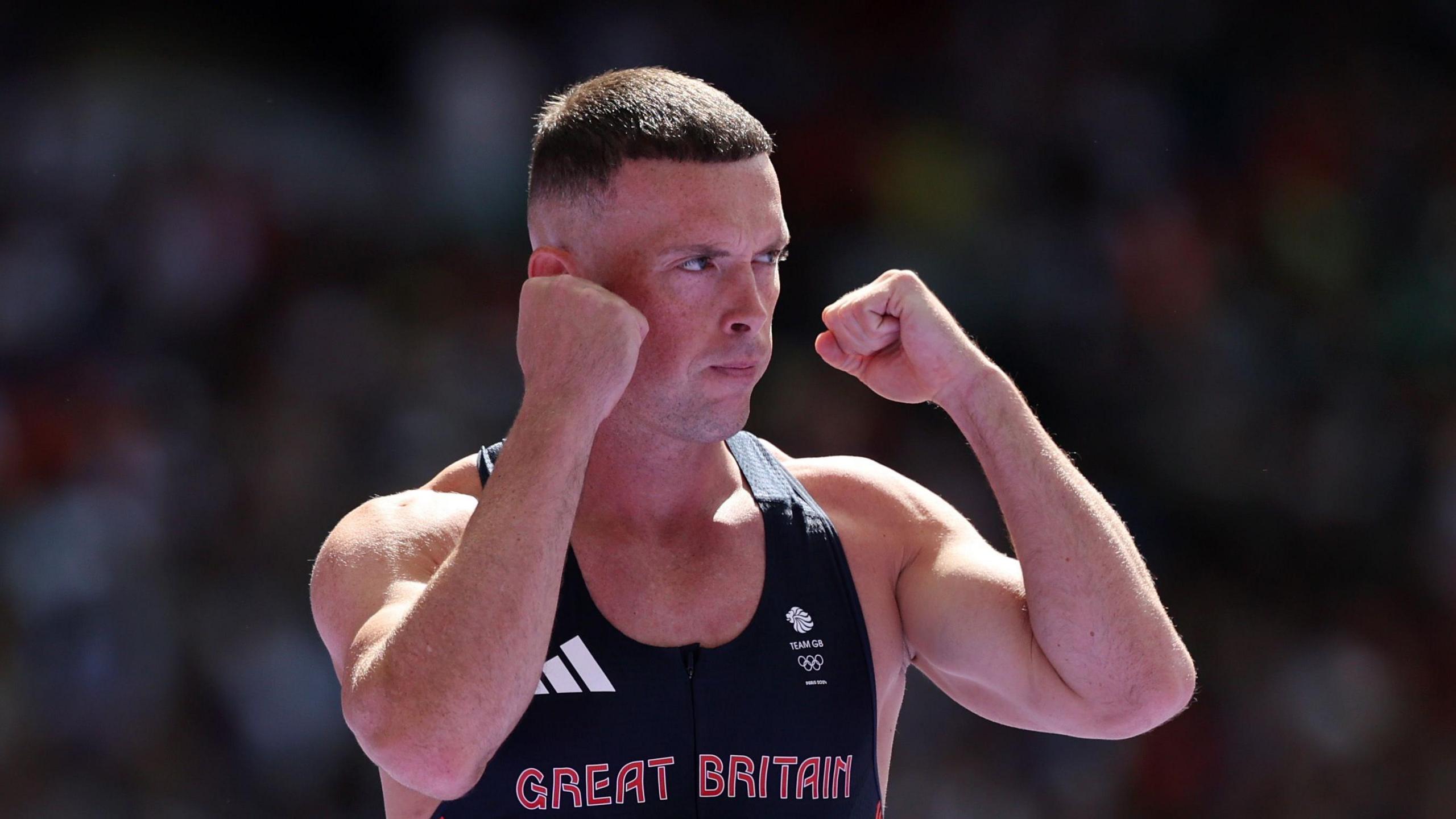Richard Kilty, with both arms raised and fists clenched, ready to race at 2024 Olympics in Paris