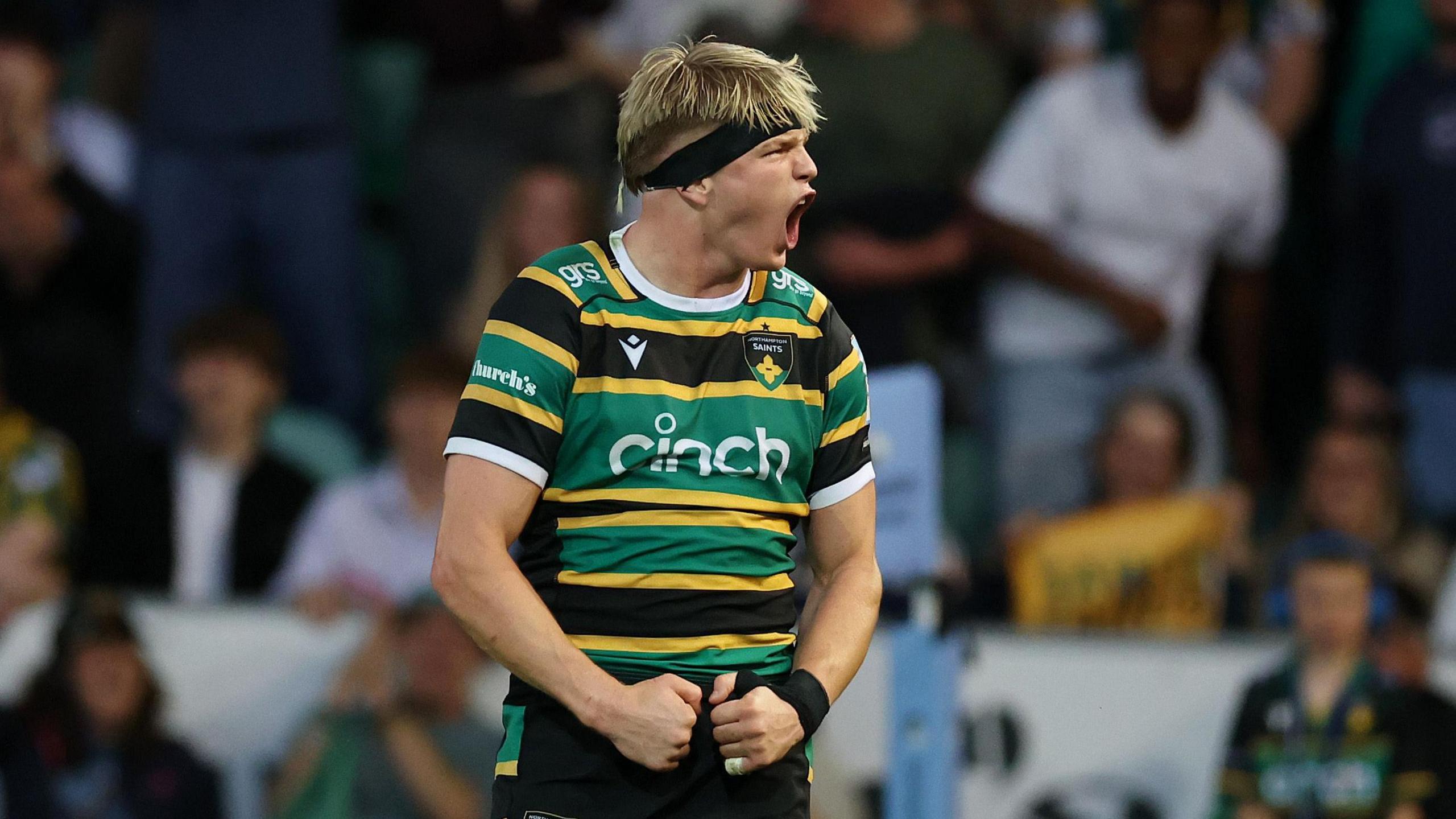 Henry Pollock cheering, with his hands clenched, wearing his black, yellow and green striped Northampton Saints kit and a black headband, during their Gallagher Prem Rugby semi-final win against Leicester Tigers
