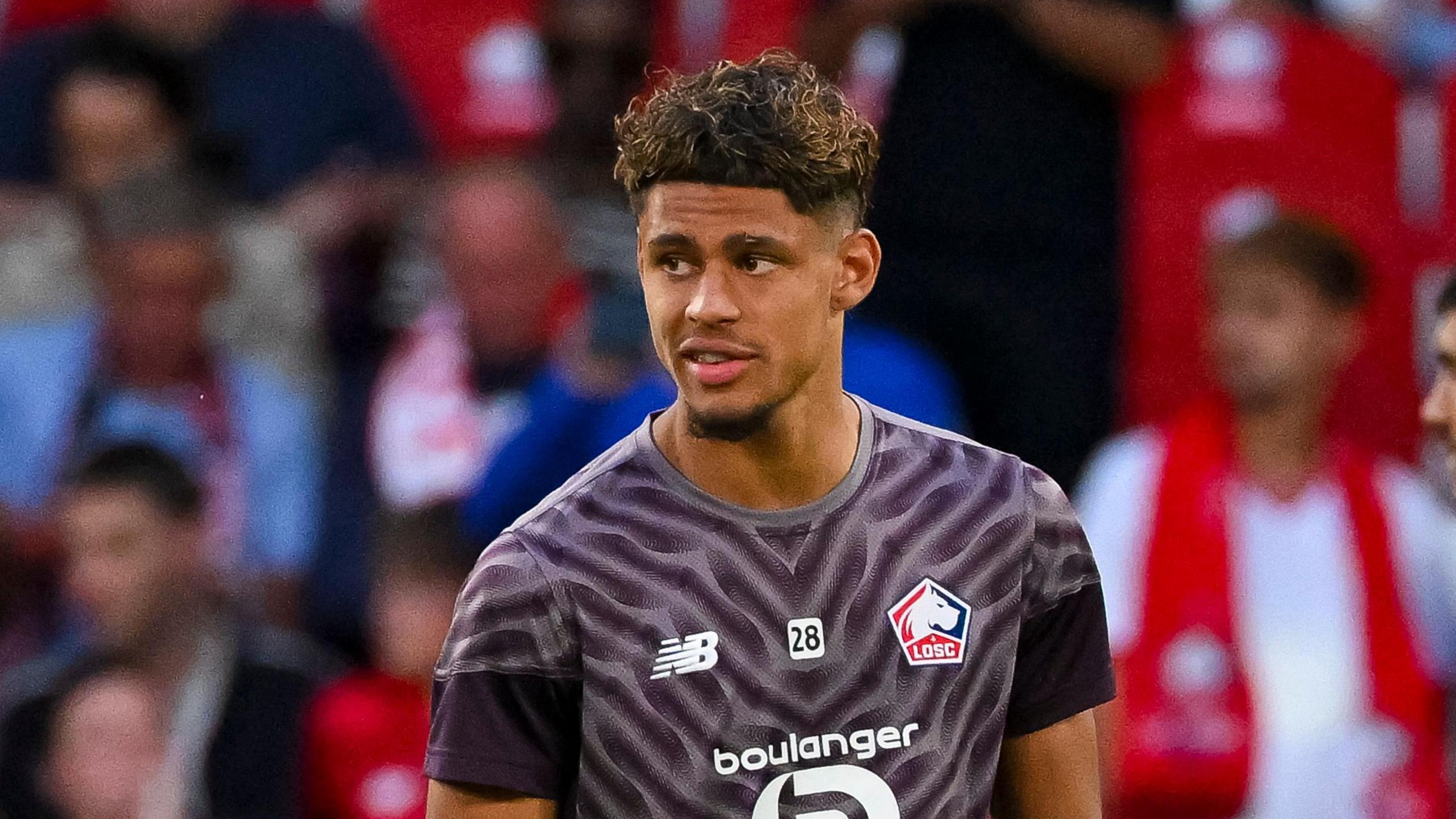 Ugo Raghouber with a number 28 in the middle of his chest, in between the Lille badge and the kit manufacturer's logo, warming up ahead of a match for the French club 