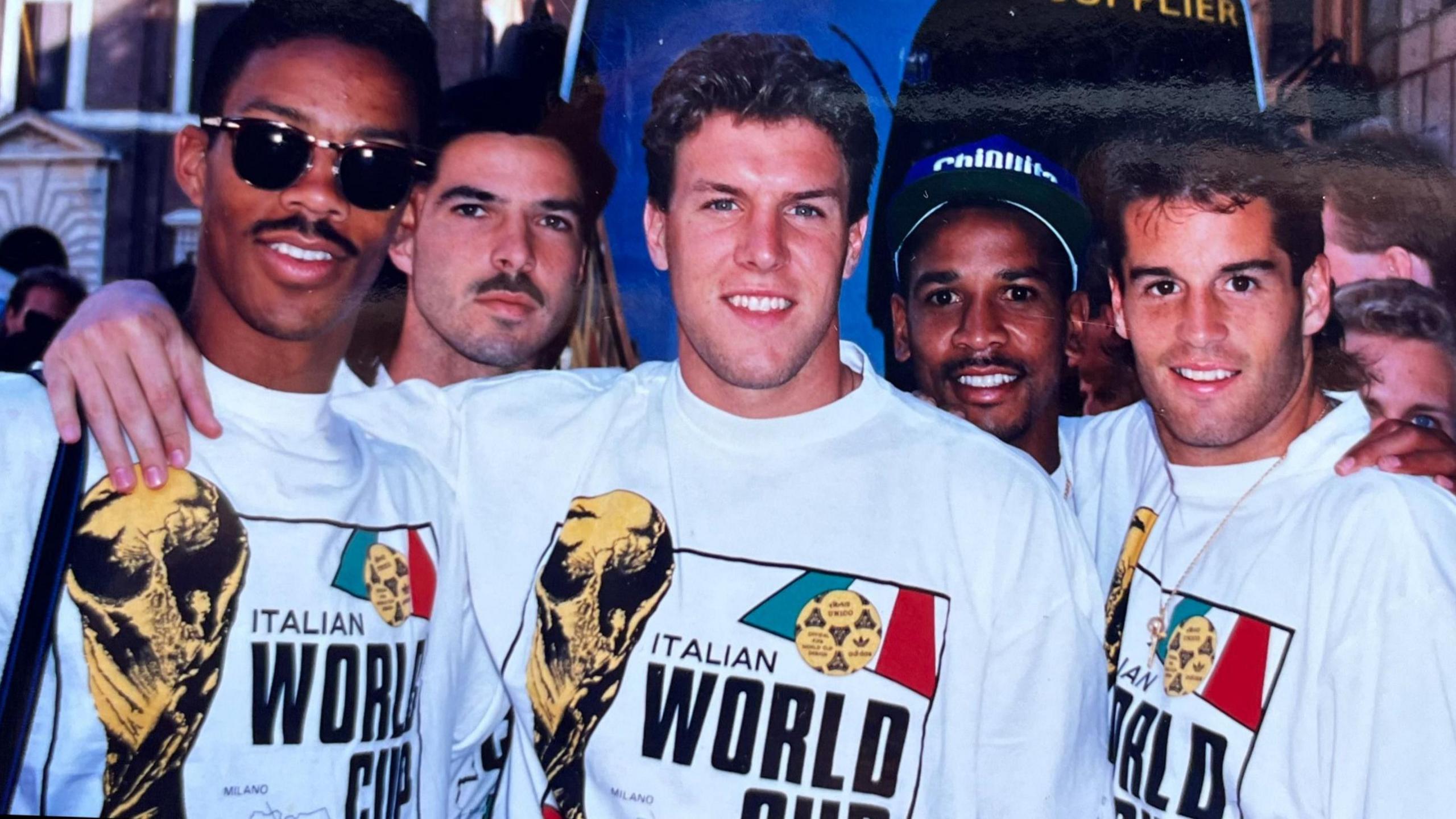Desmond Armstrong and other members of the USA team in T-shirts carrying the words 'Italian World Cup' and featuring an image of the World Cup trophy