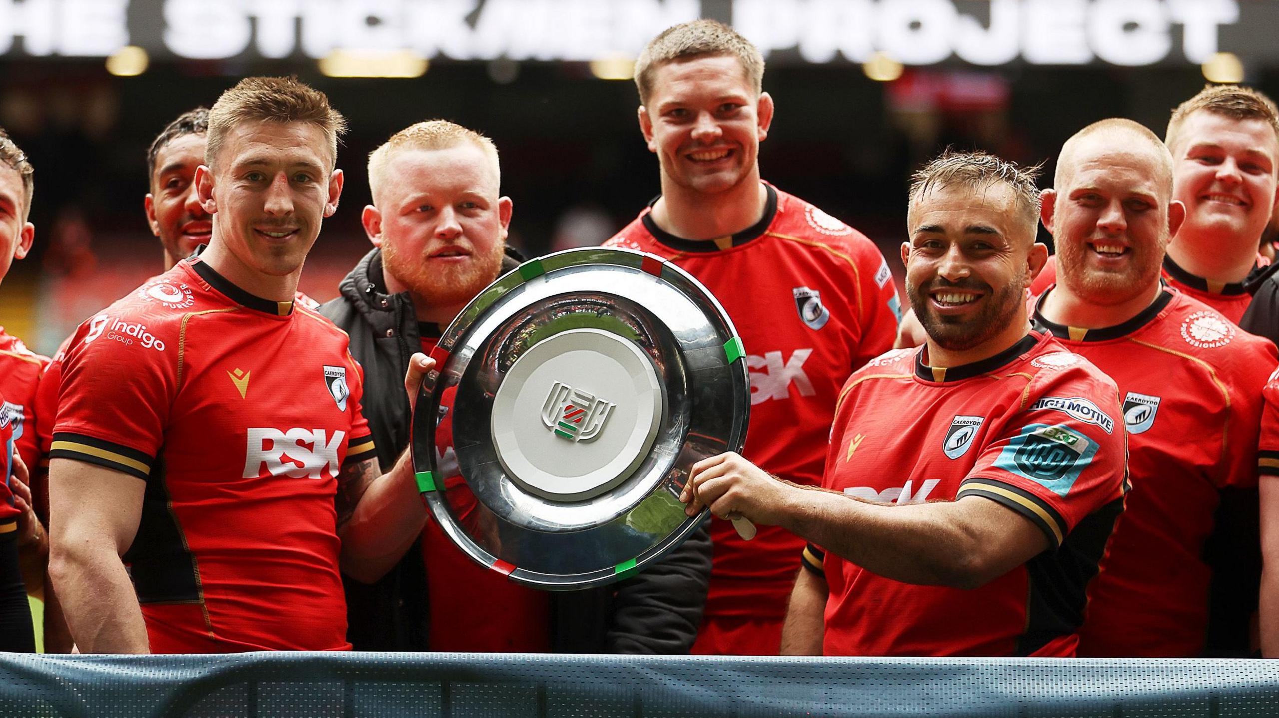 Cardiff players in red shirts holding up the silver Welsh Shield
