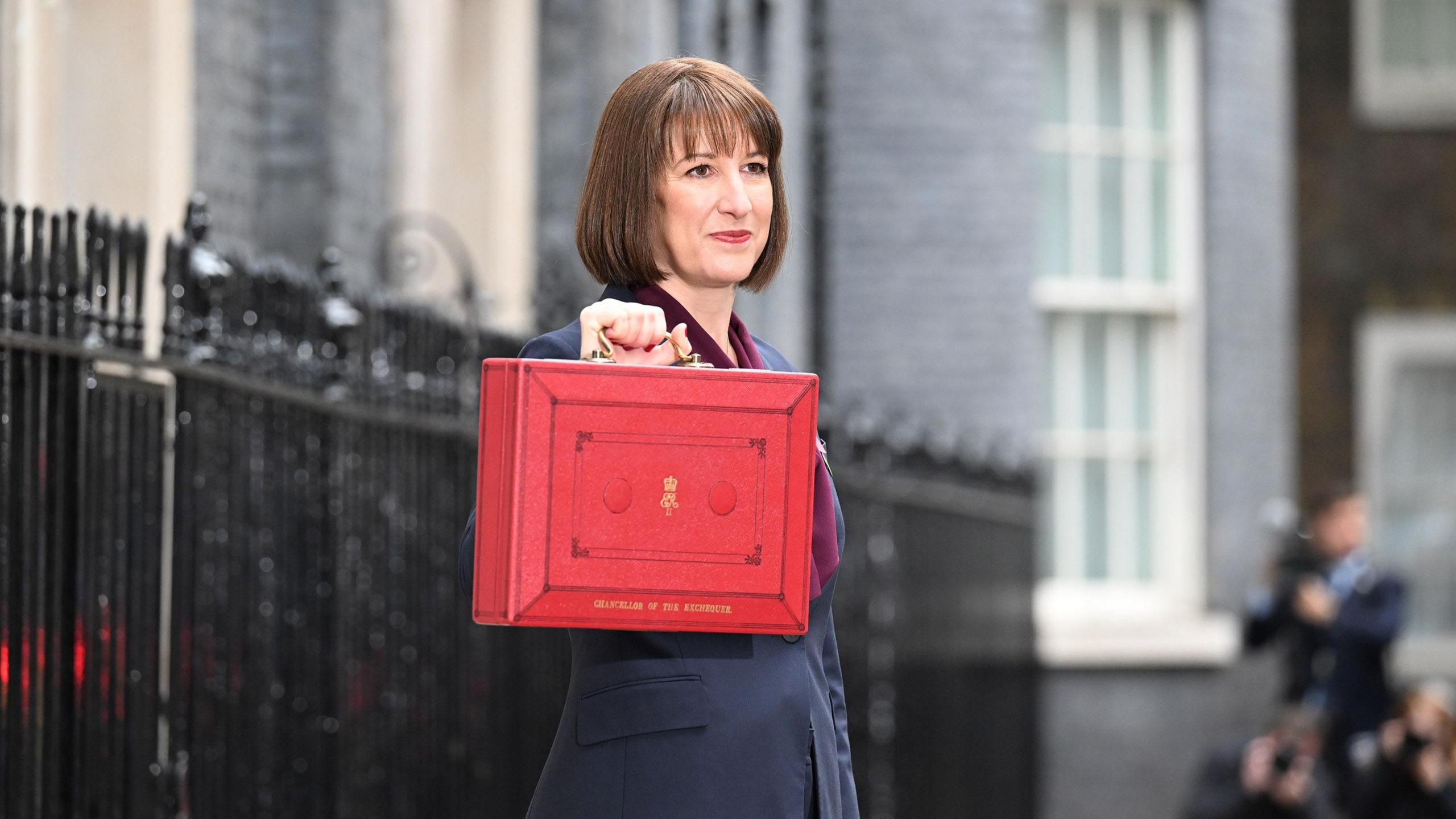 Chancellor Rachel Reeves standing outside 11 Downing Street, holding up the red box in the traditional Budget Day photo call.