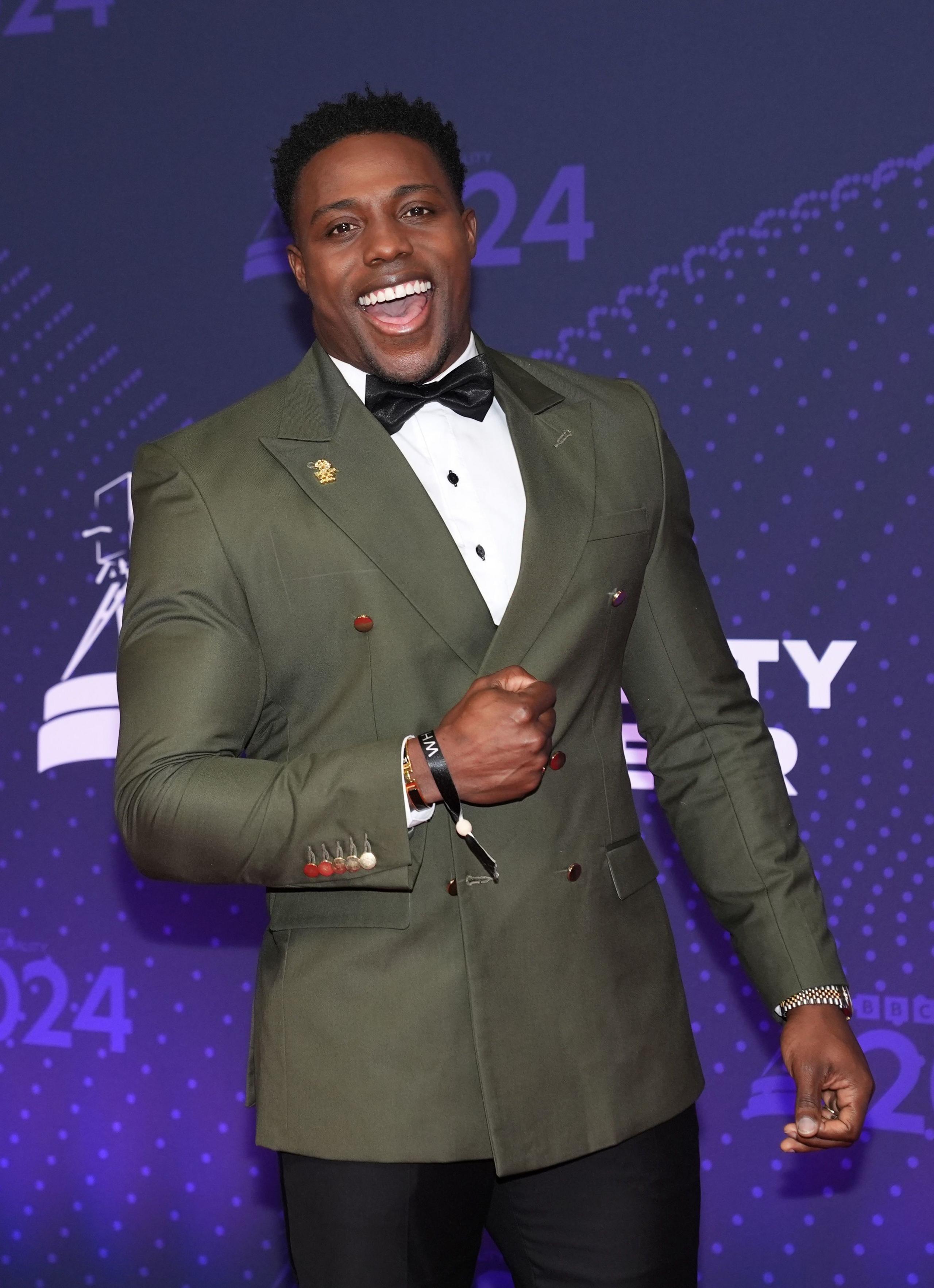 harry aikines-aryeetey posing for a photo at bbc sports personality of the year wearing a suit and smiling