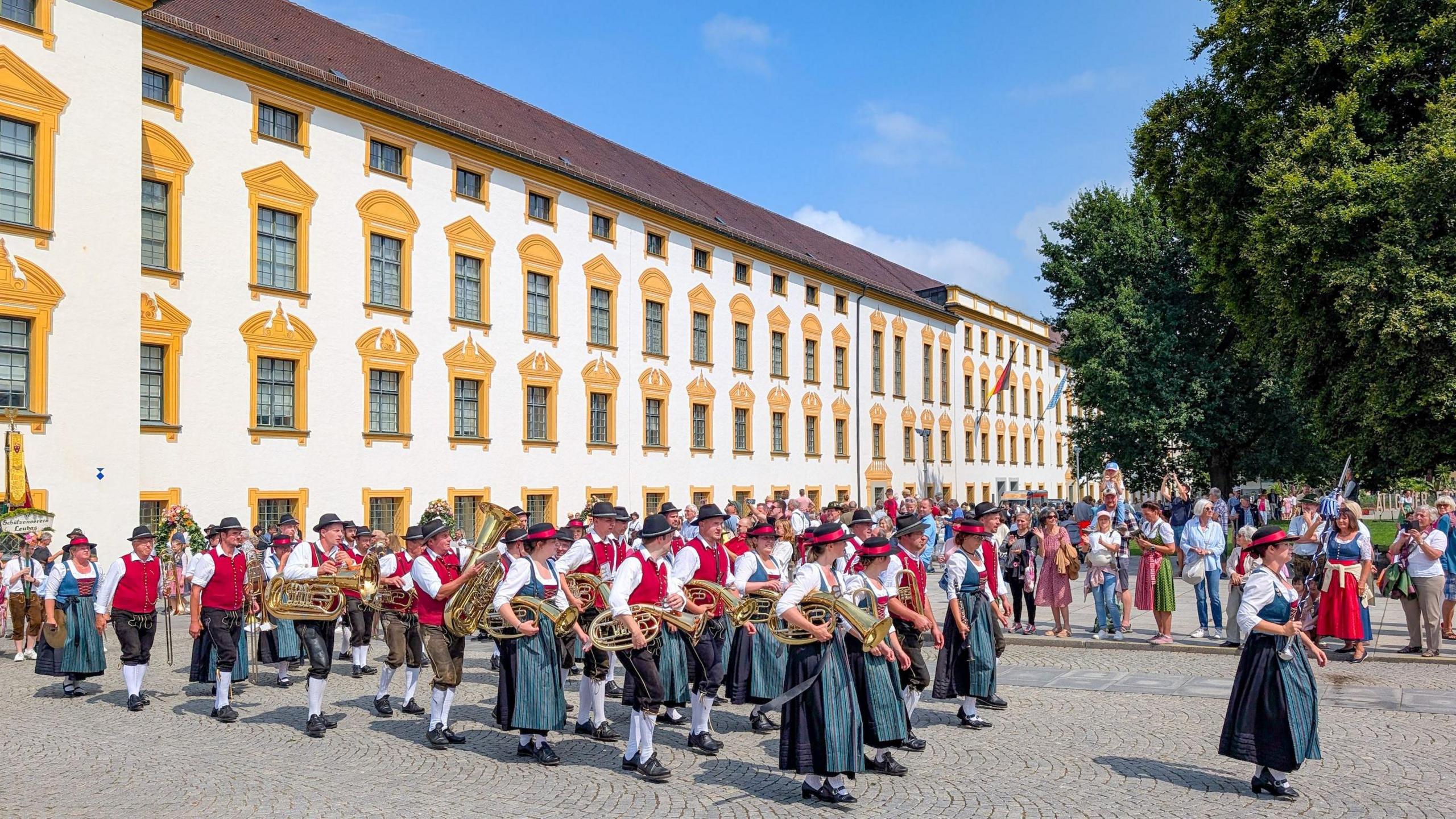 People in traditional Bavarian dress take part in a parade carrying brass instruments