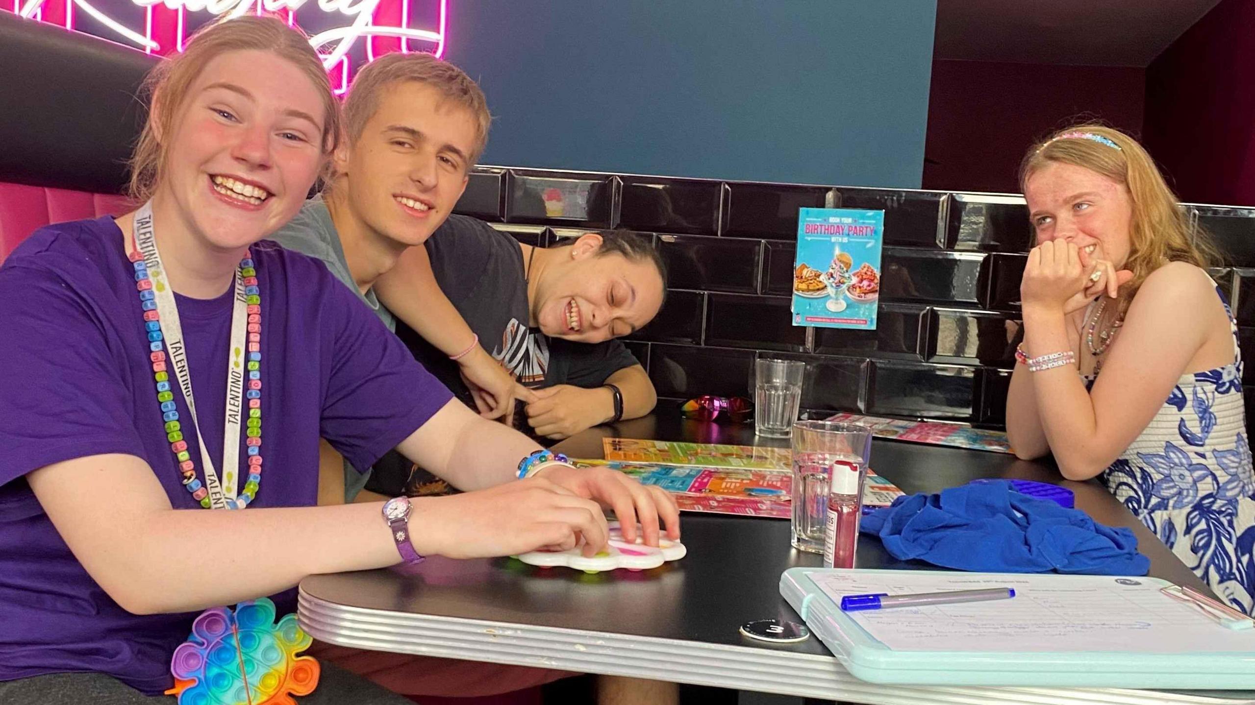 A group of young people sitting at a table with drawings.