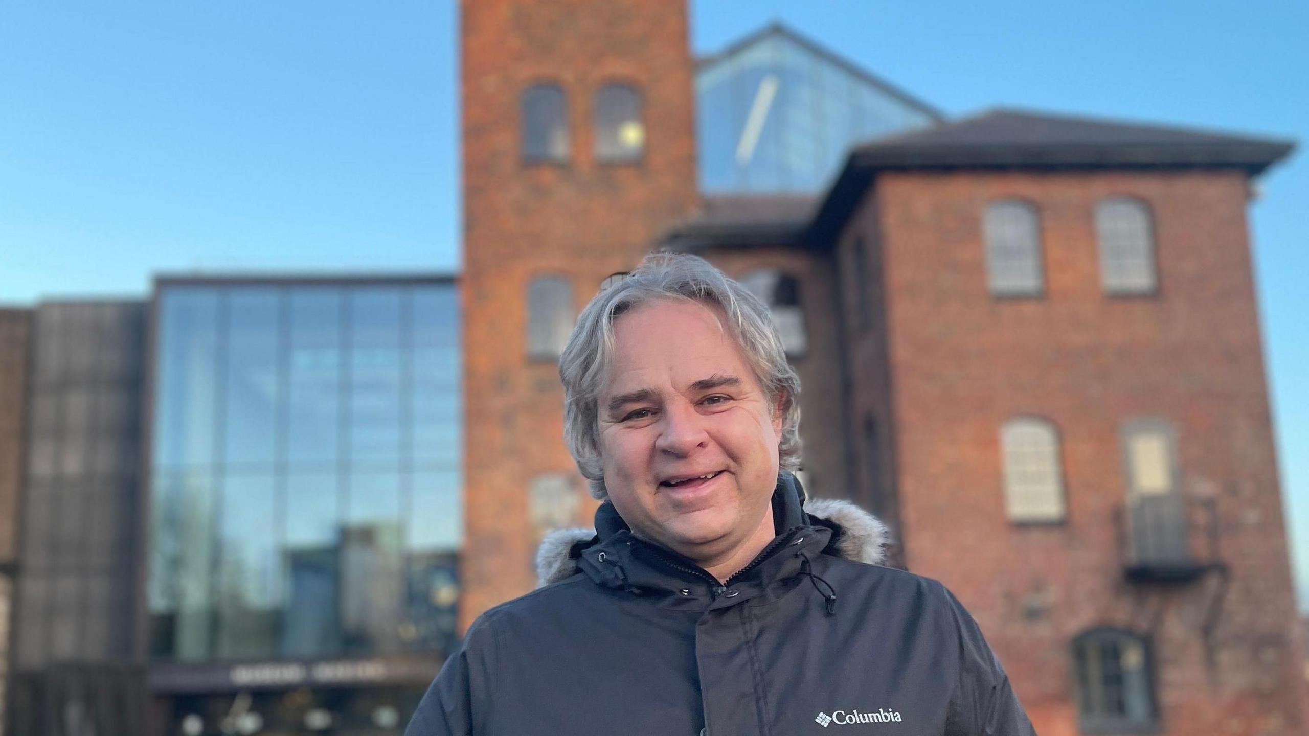 A man with grey hair and wearing a coat stood outside the museum of making in Derby city centre