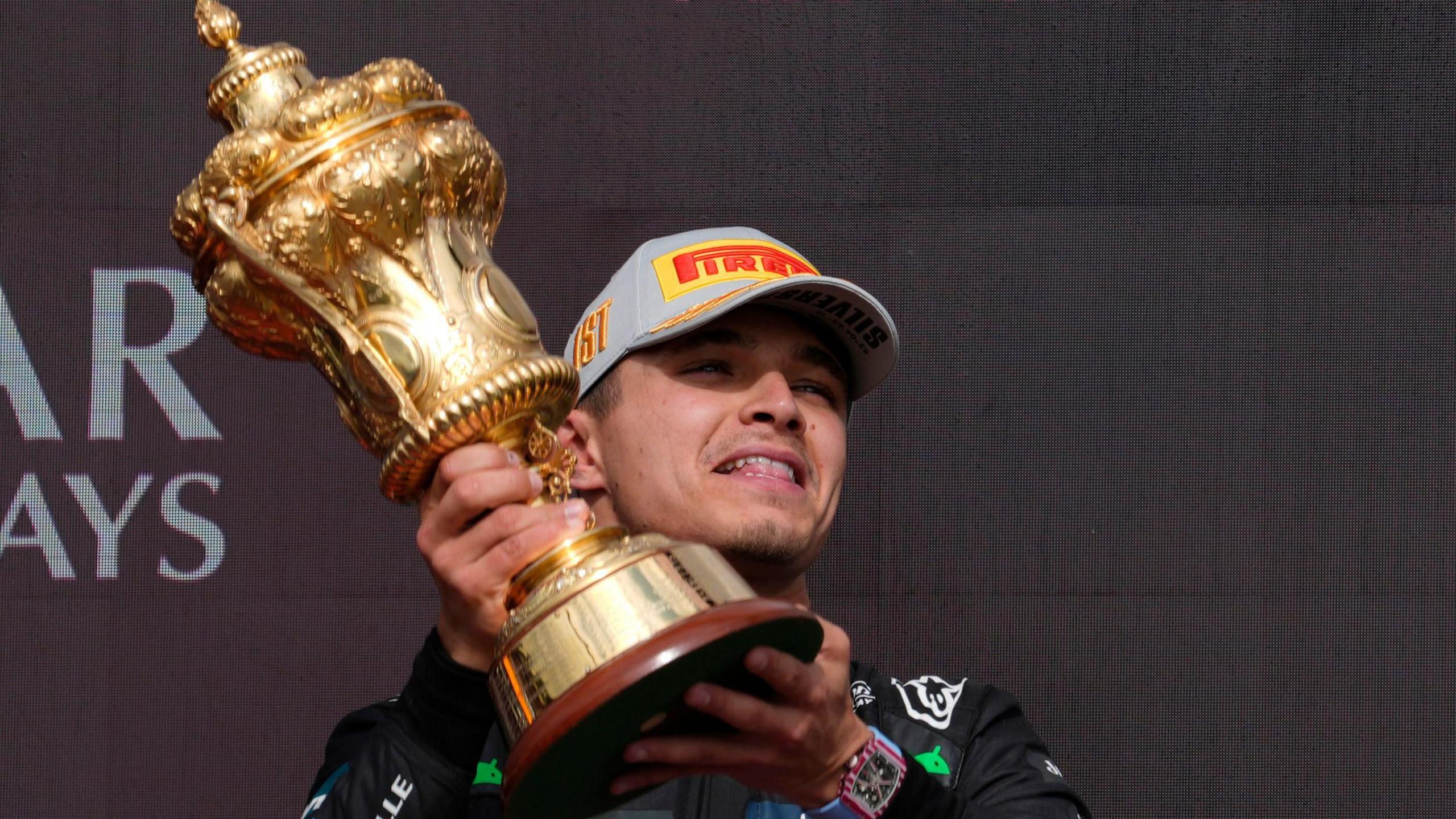 Lando Norris holds the winner's trophy on the podium after winning the British Grand Prix