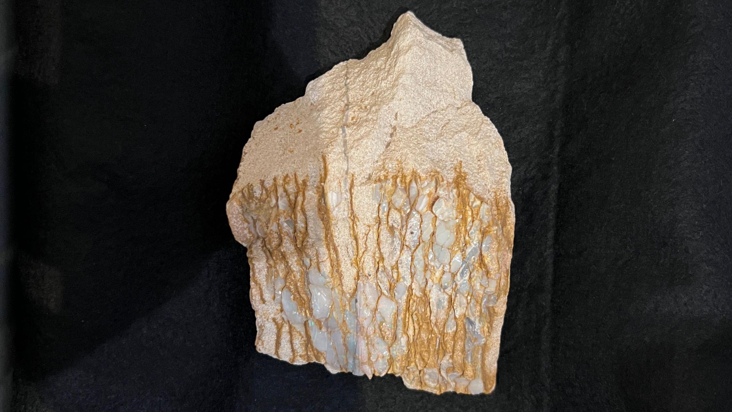 An opal gem stone on a black velvet background