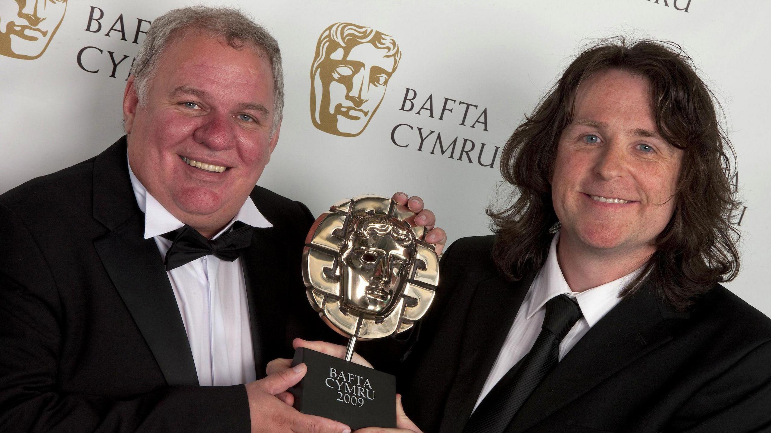 Andrew Jenkins a Peter Watkins-Hughes yn dal gwobr Bafta Cymru