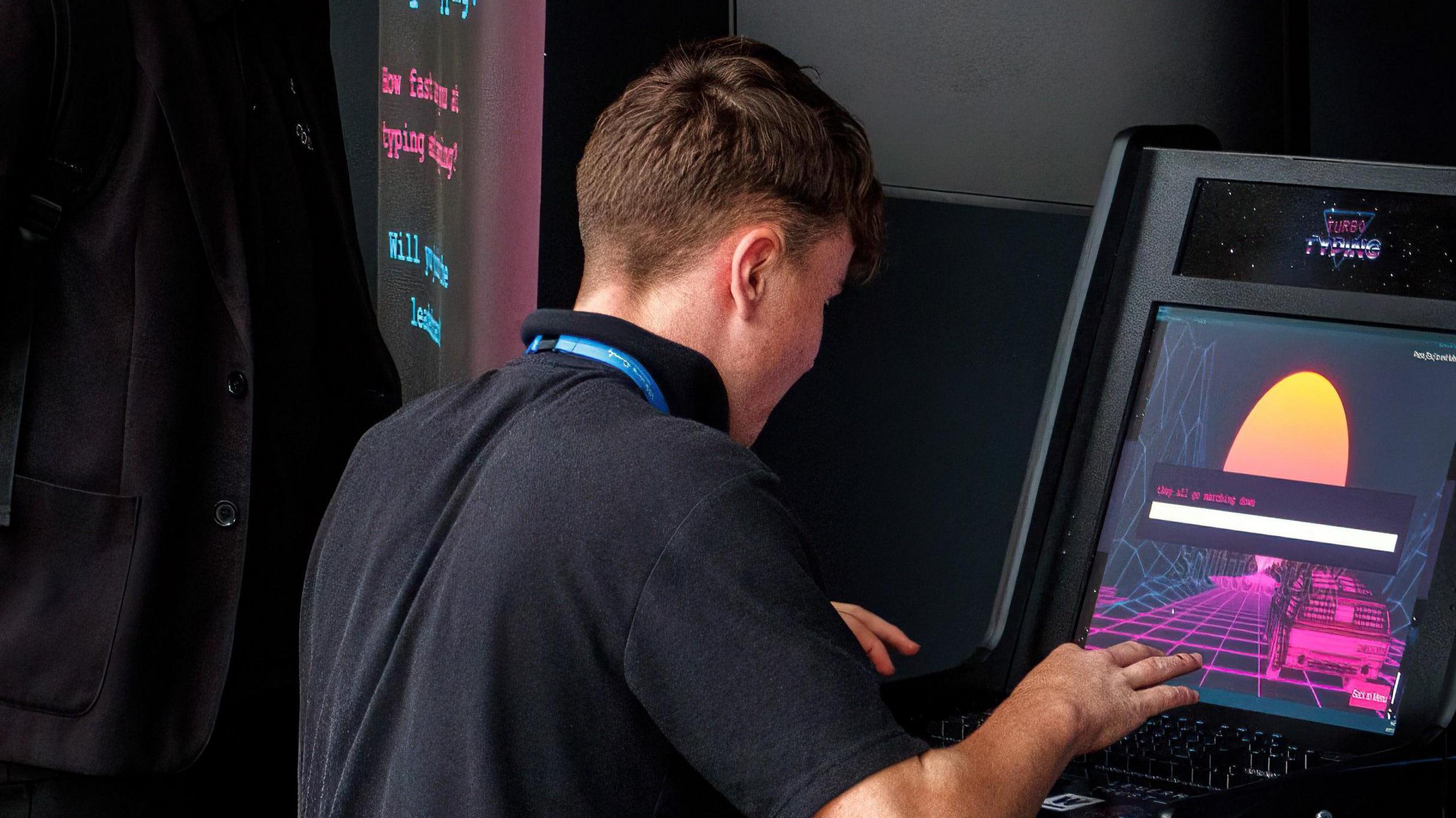 A teenage boy wearing a black polo top plays on an electronic gambling machine with his back to the camera.