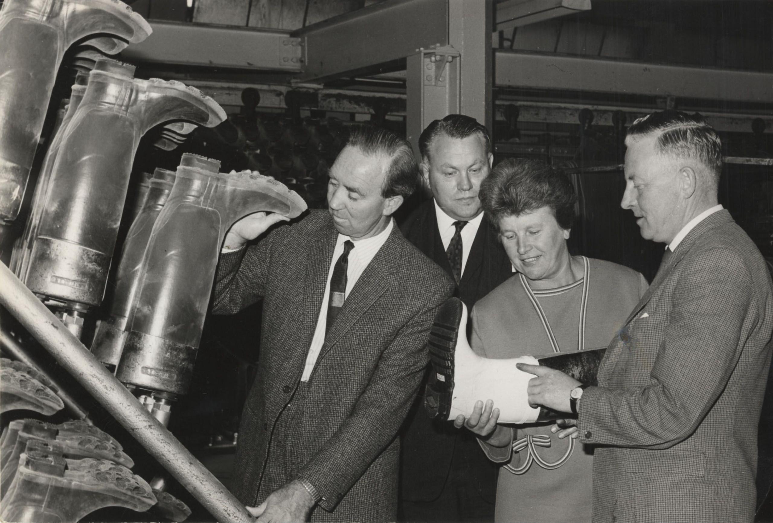 Three men and a woman check out the wellington boots coming off a production line