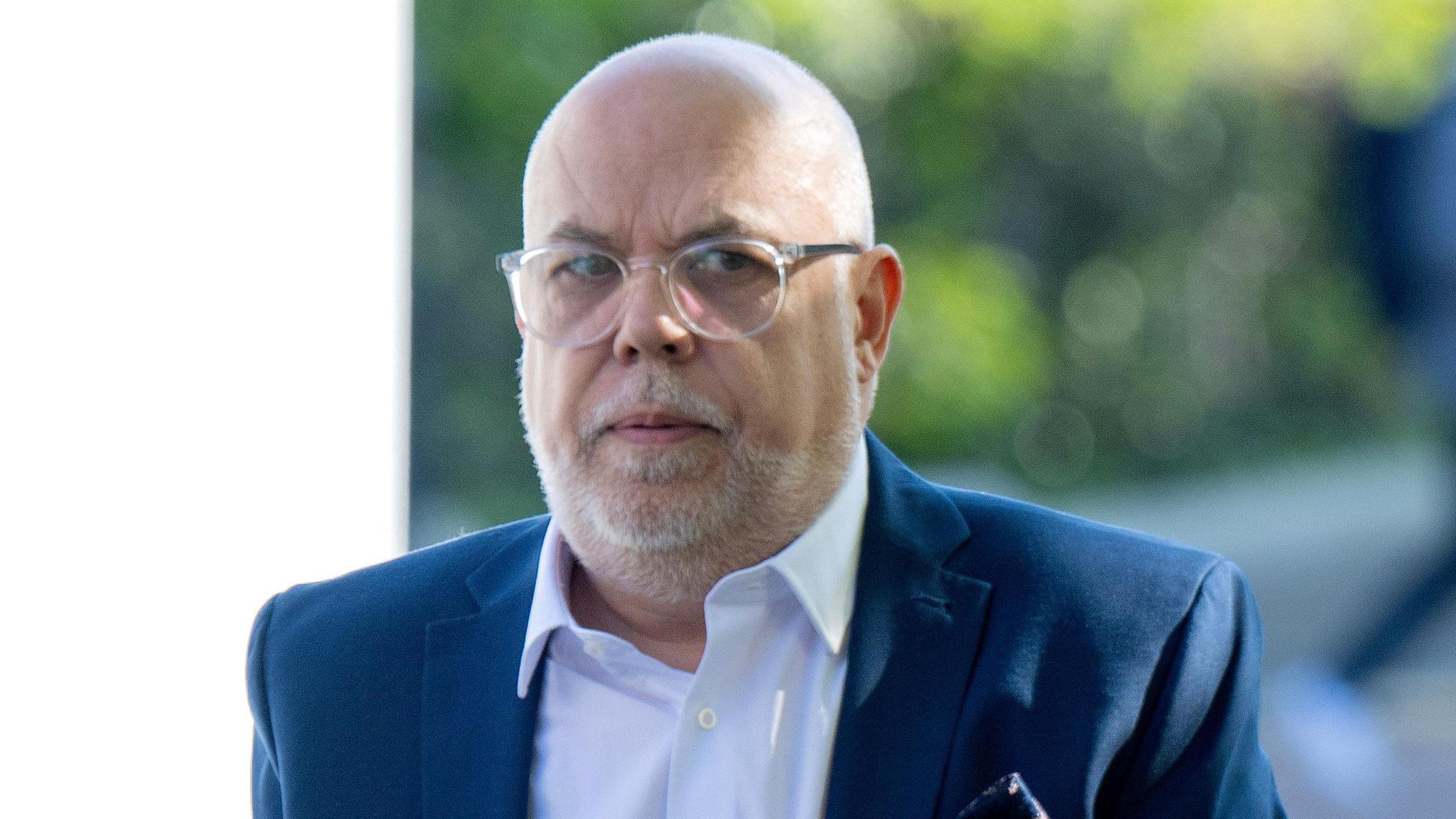 Photograph of teacher Jonathan Coombs, 54, pictured leaving Cardiff Crown Court. He is bald and wears round reading glasses. He has a short trim silver beard.