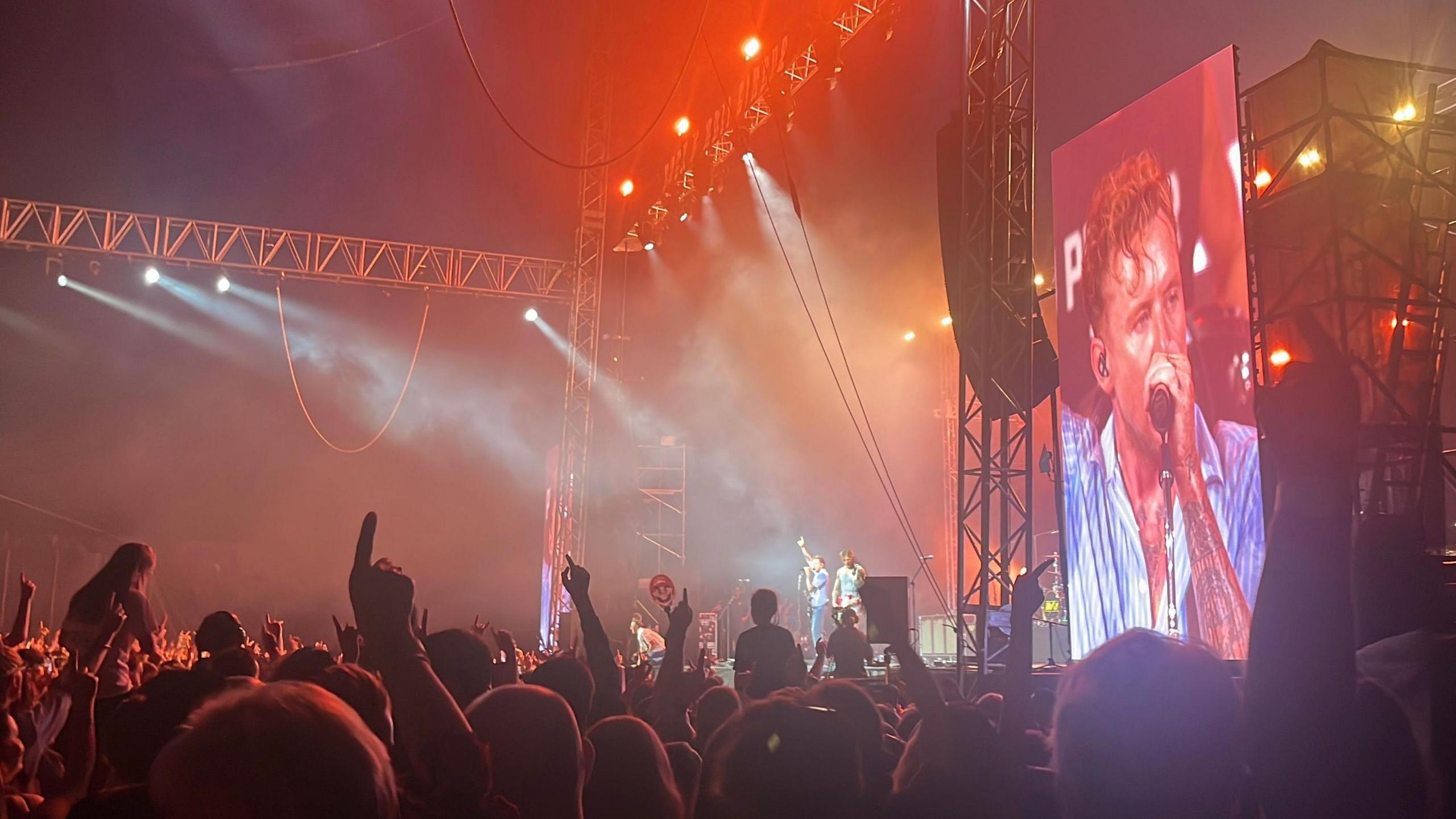 Crowds gather to watch McFly at the Rock N Roll Circus Festival. Danny Jones is on a big digital screen.