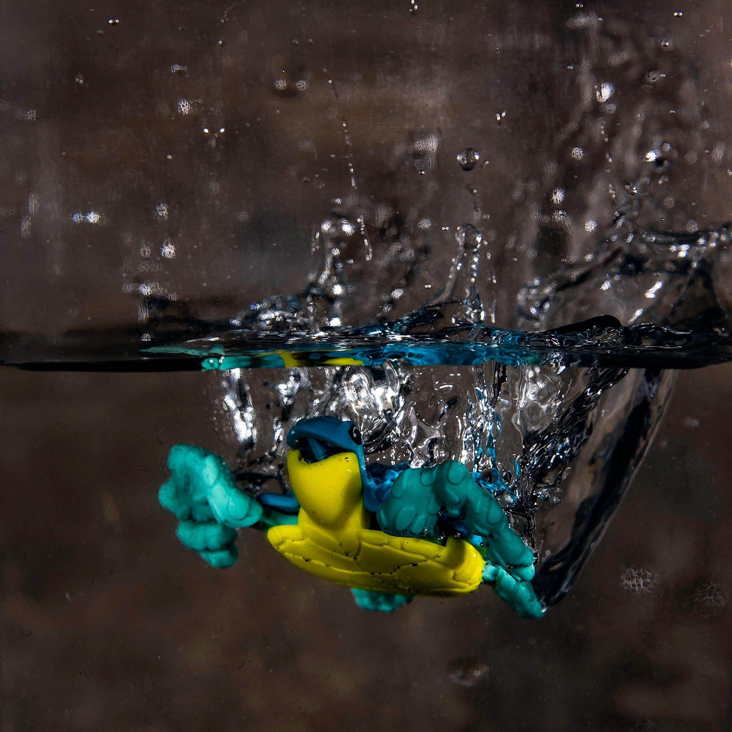 A toy turtle splashes as it enters a glass of water