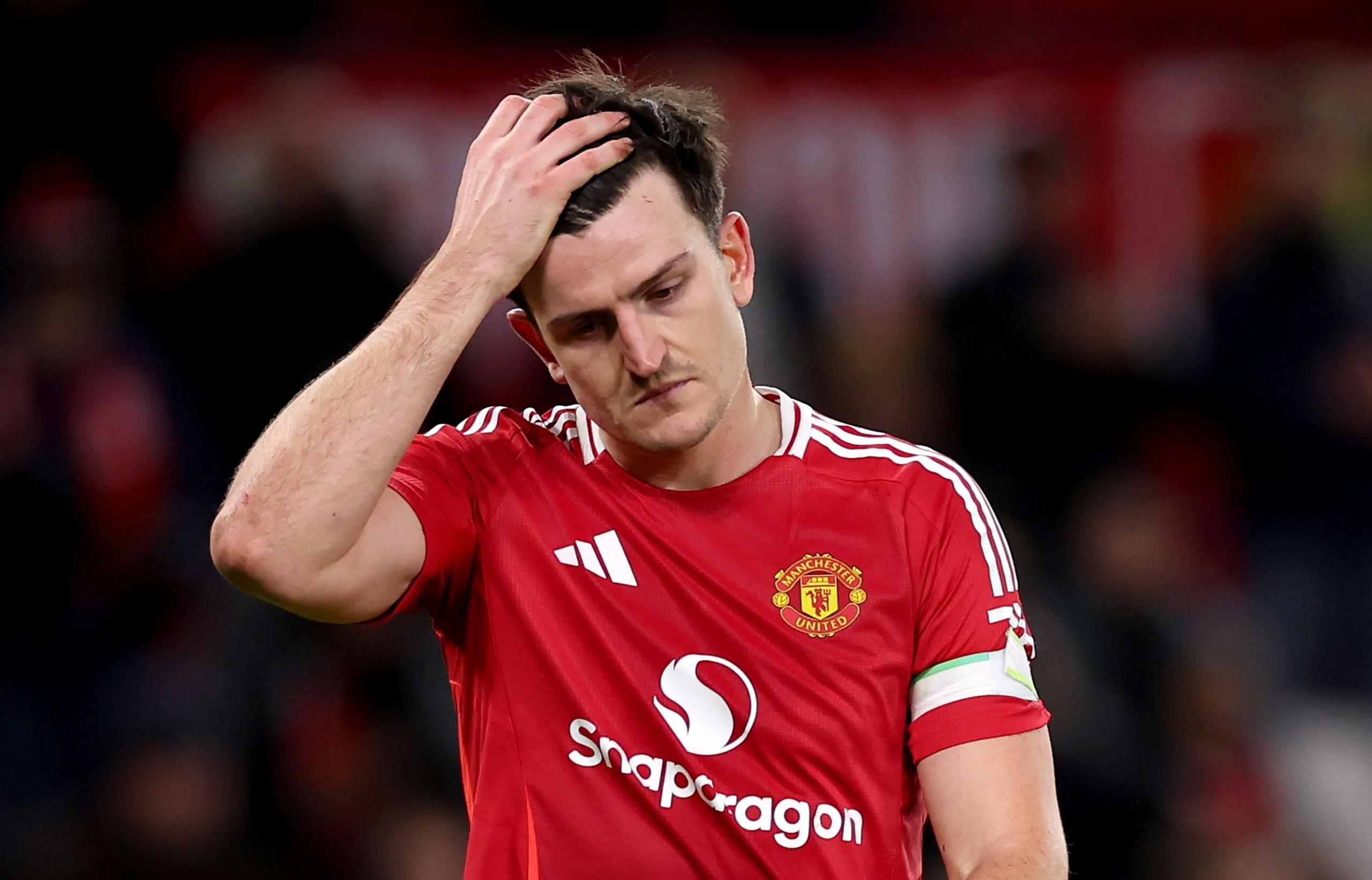 Harry Maguire in a red Manchester United shirt with his hand on his head