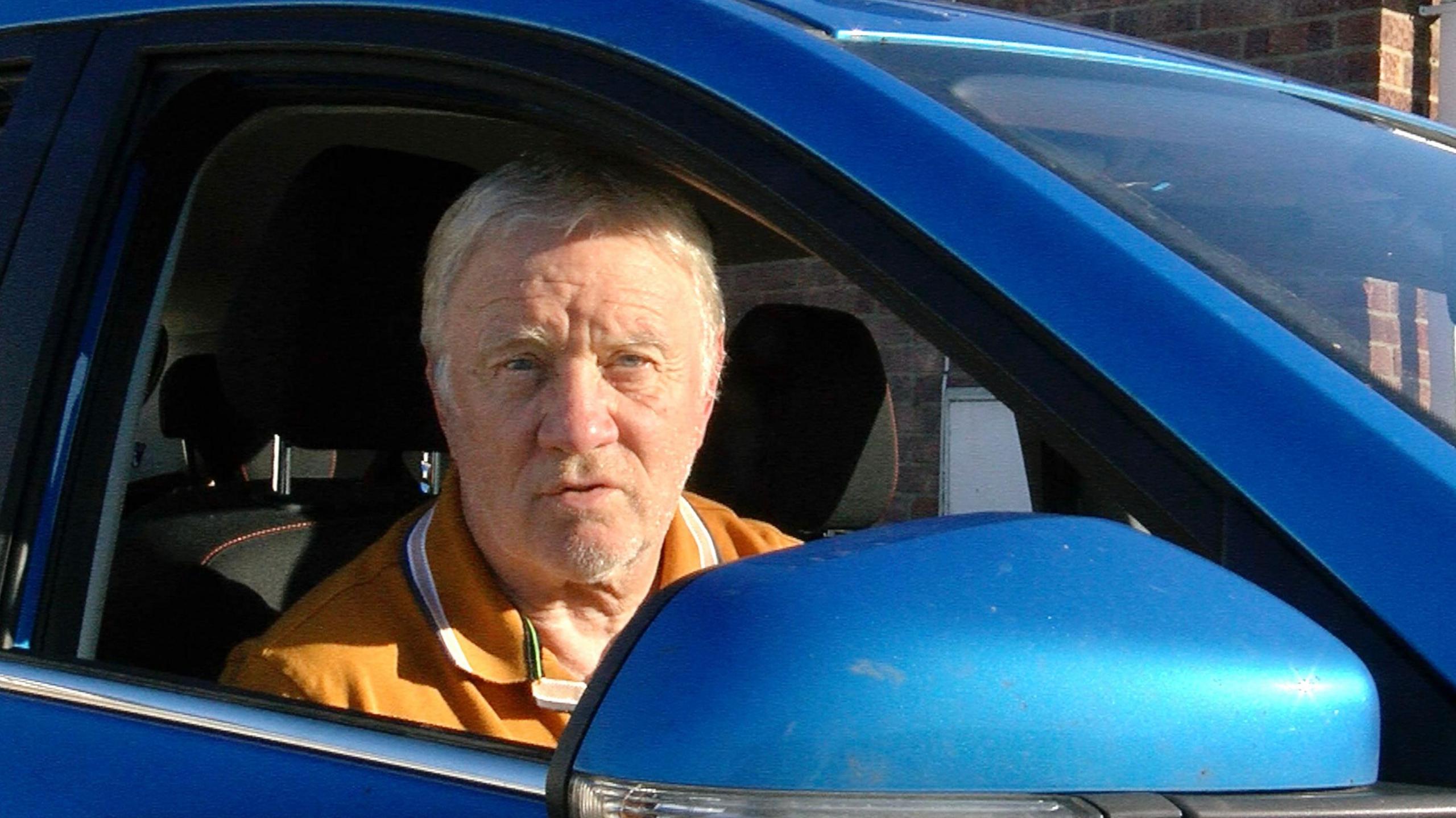 Driver Phil Coulridge sitting inside his blue car.