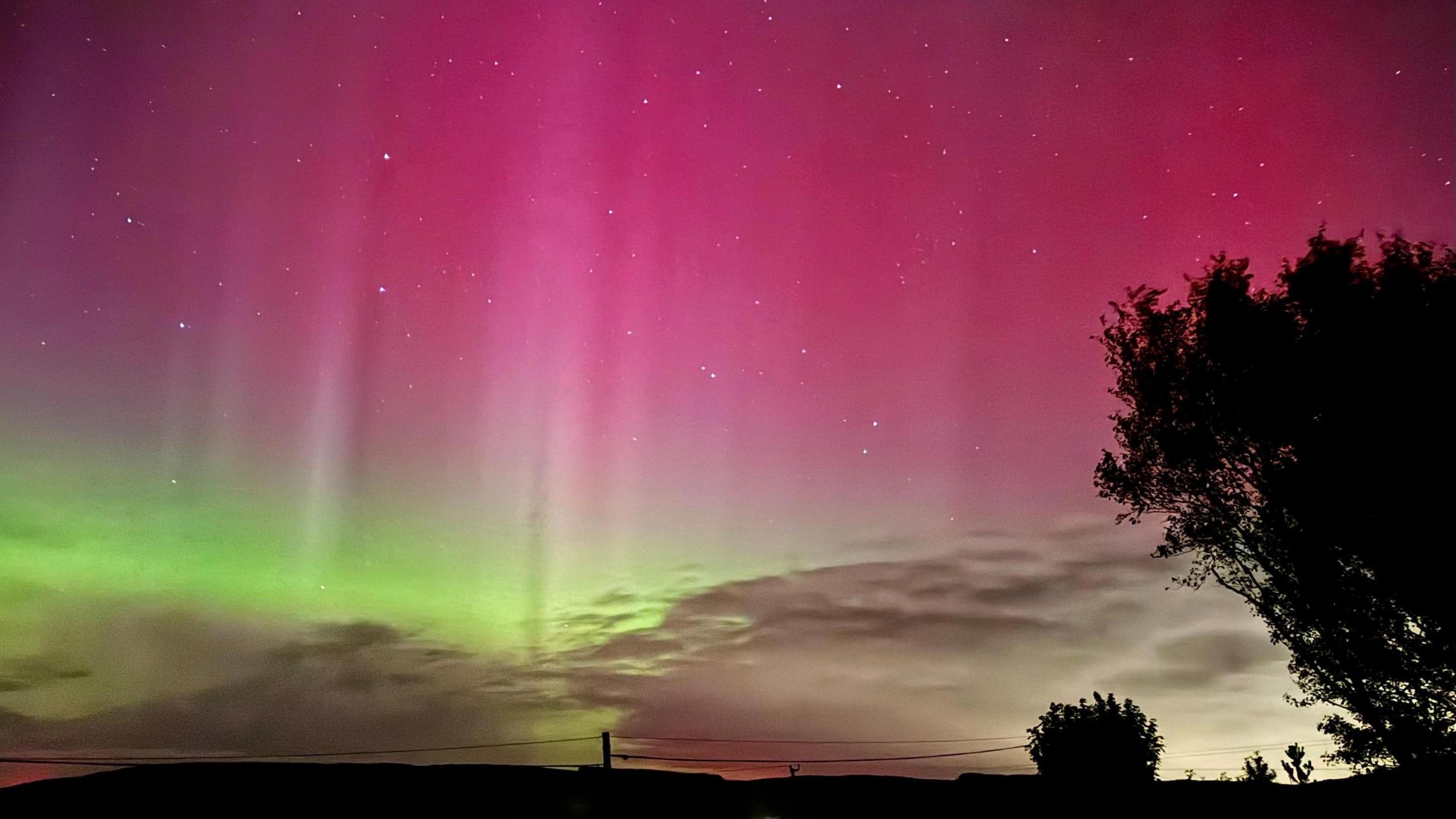 A picture of the sky which is lit up pink and green.