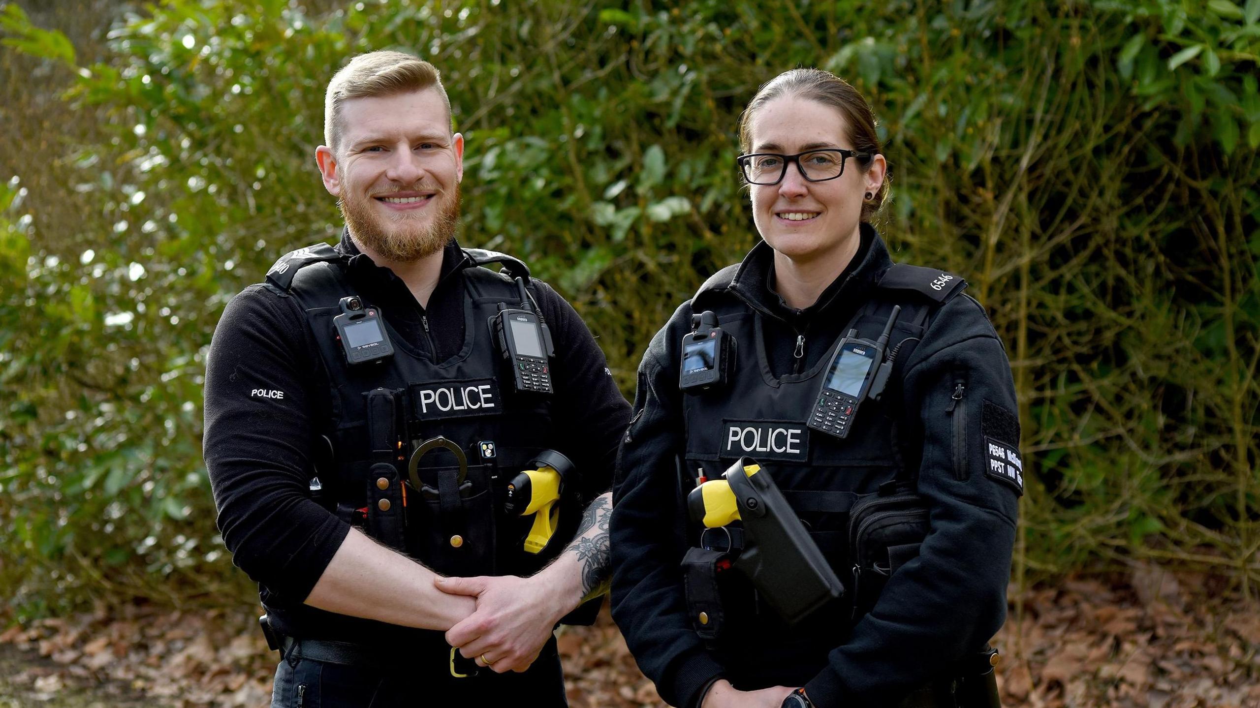 The officers in uniform standing next to each other smiling. Sgt Chris Smith on the left and Sophie McDiarmid on the right with glasses. 