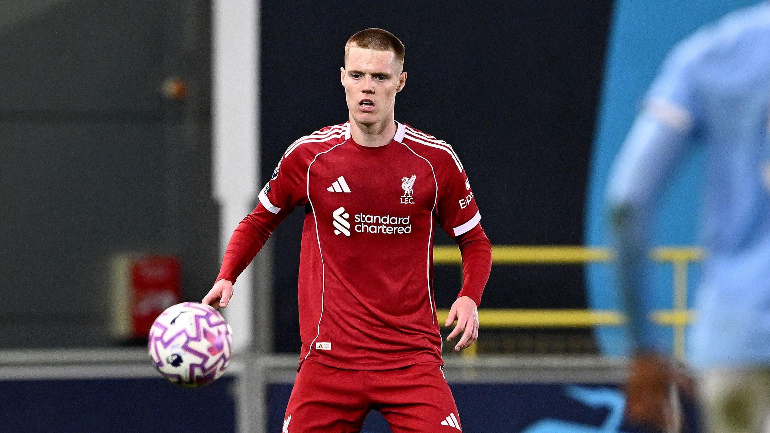 An image of Carter Pinnington looking at the ball while playing for Liverpool's Under-21s team in their red home kit