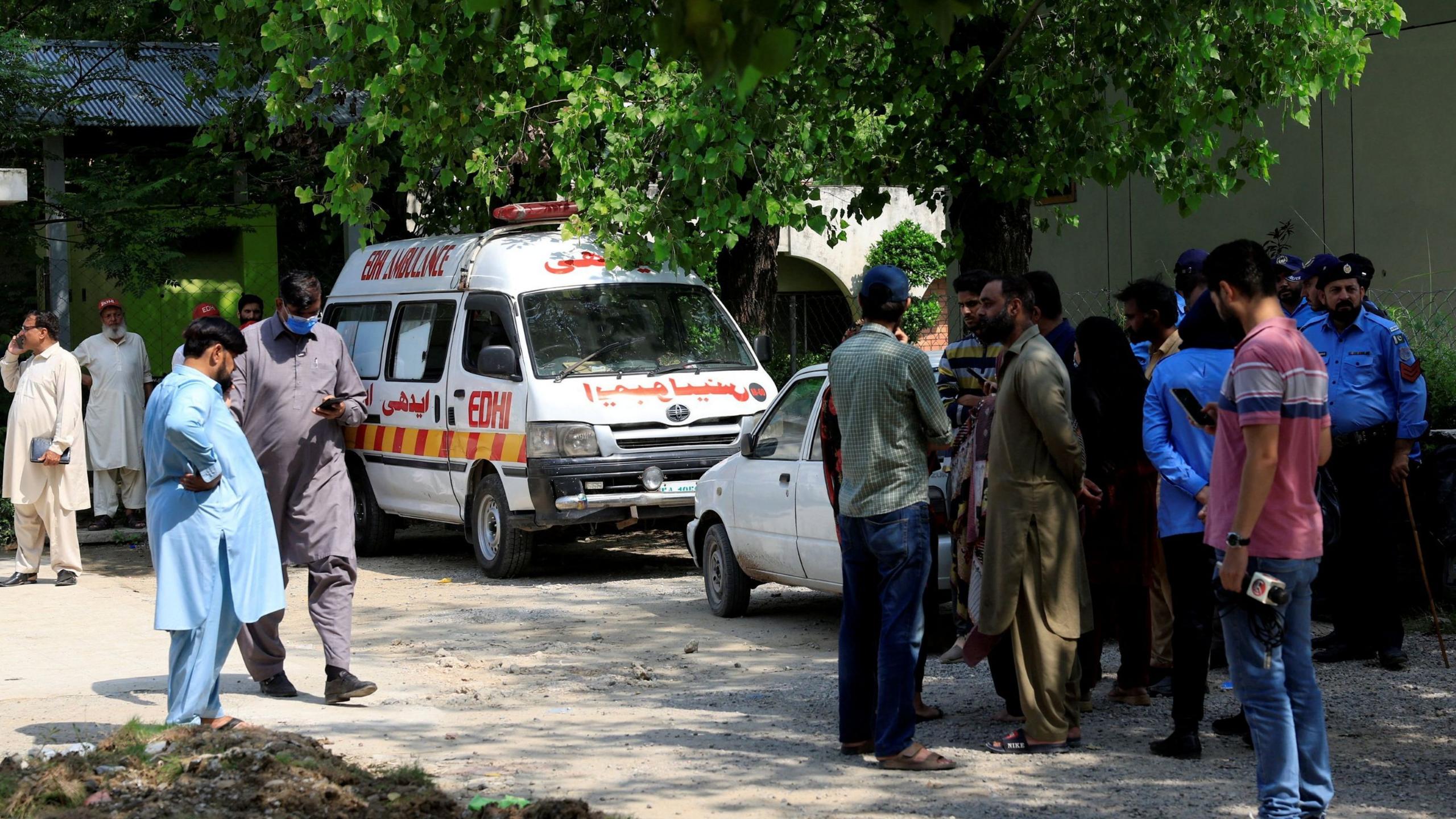 Family members and police officers stand outside a mortuary following a deadly fire at the Pakistan Institute of Medical Sciences (PIMS) hospital in Islamabad, Pakistan, August 26, 2026.