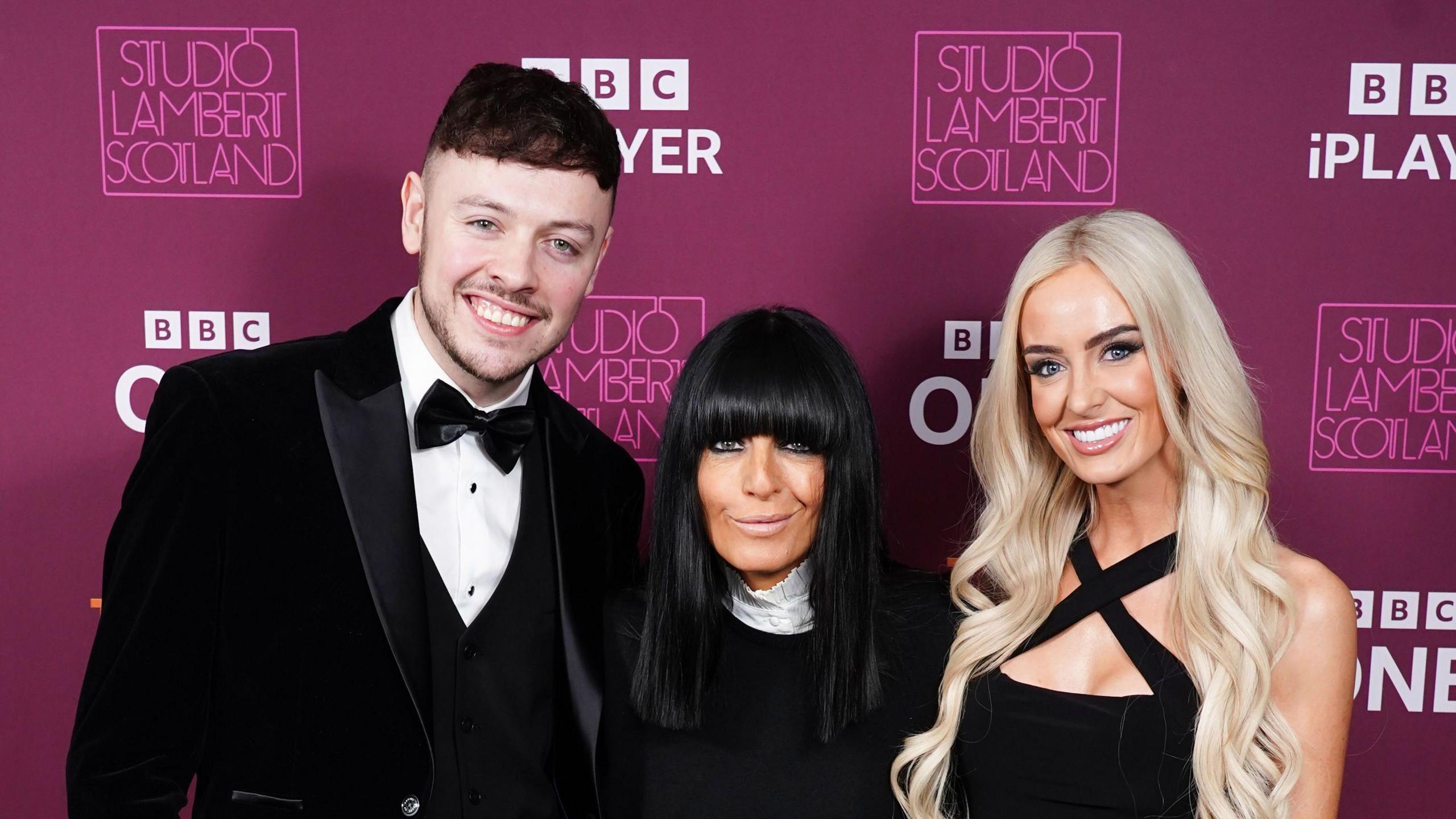 The Traitors series three winners Jake Brown and Leanne Quigley, pictured with presenter Claudia Winkleman, wearing black tie 