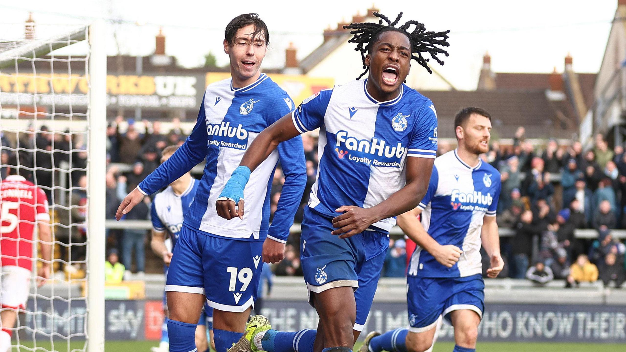 Three Bristol Rovers players celebrate after scoring a late equaliser against Wrexham at the Memorial Stadium. Goalscorer Promise Omochere is leading the celebrations