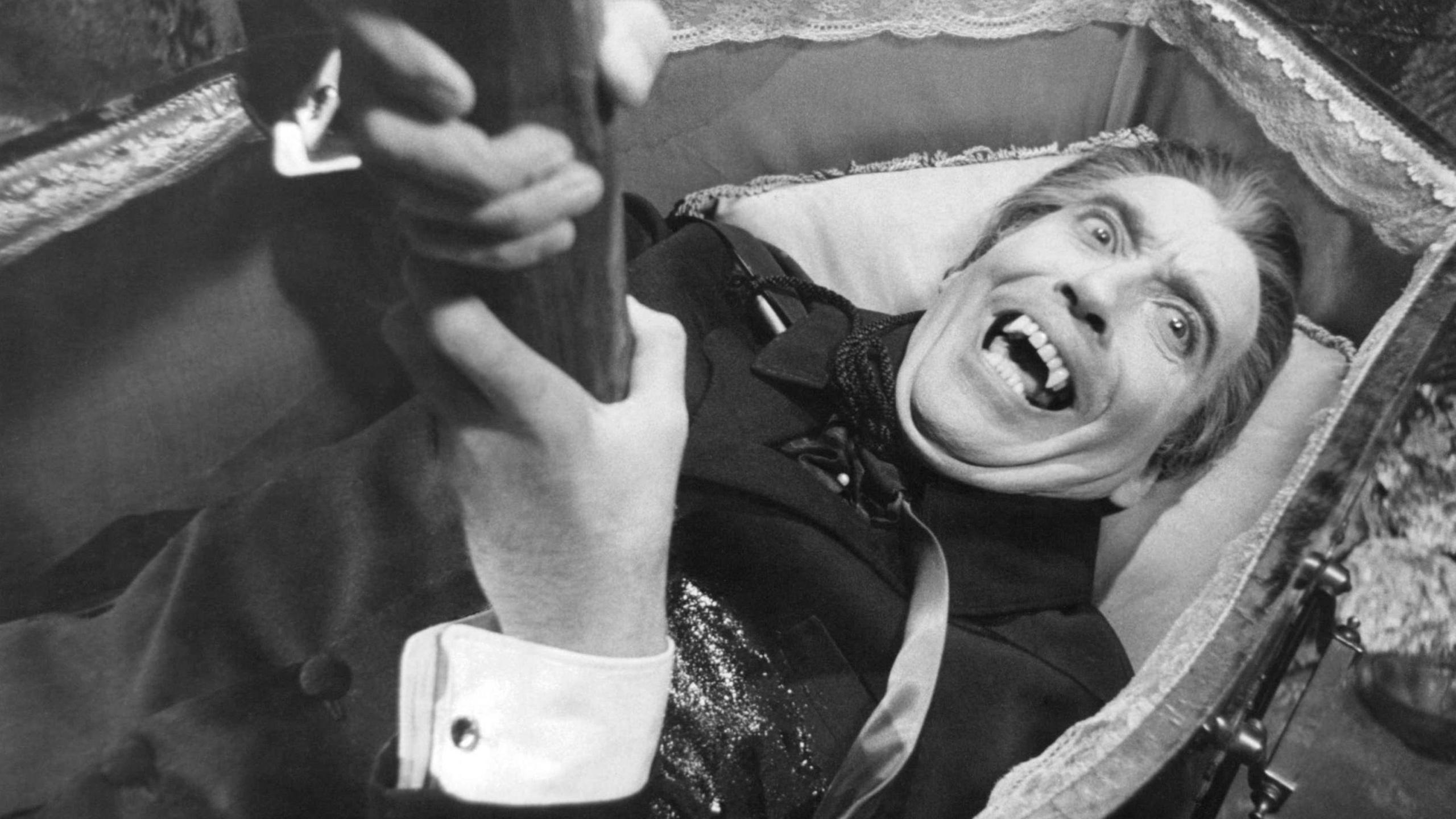 Christopher Lee as Dracula, lying in a coffin with a stake through his heart.