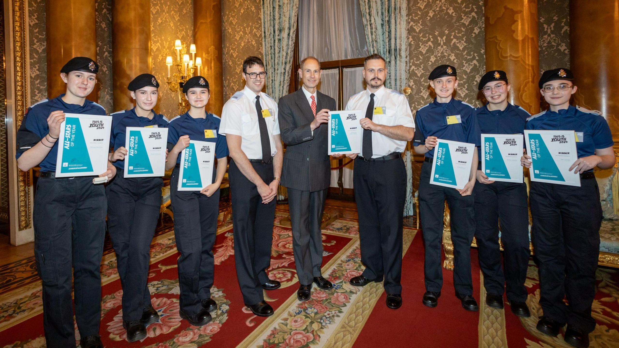 The Duke of Edinburgh in the middle stood with two Duke of Edinburgh Award group leaders as well as four teenage girls who are holding certificates