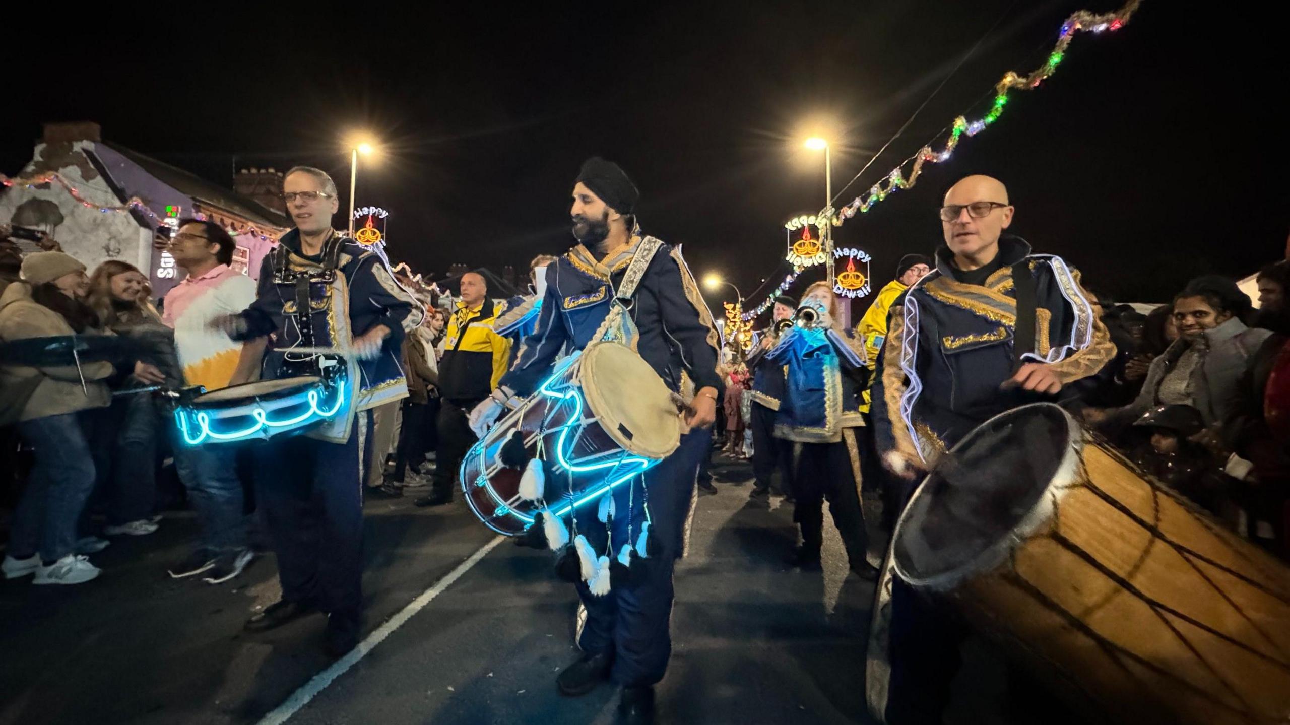 Three men in traditional outfits play drums on the Diwali parade in Leicester 