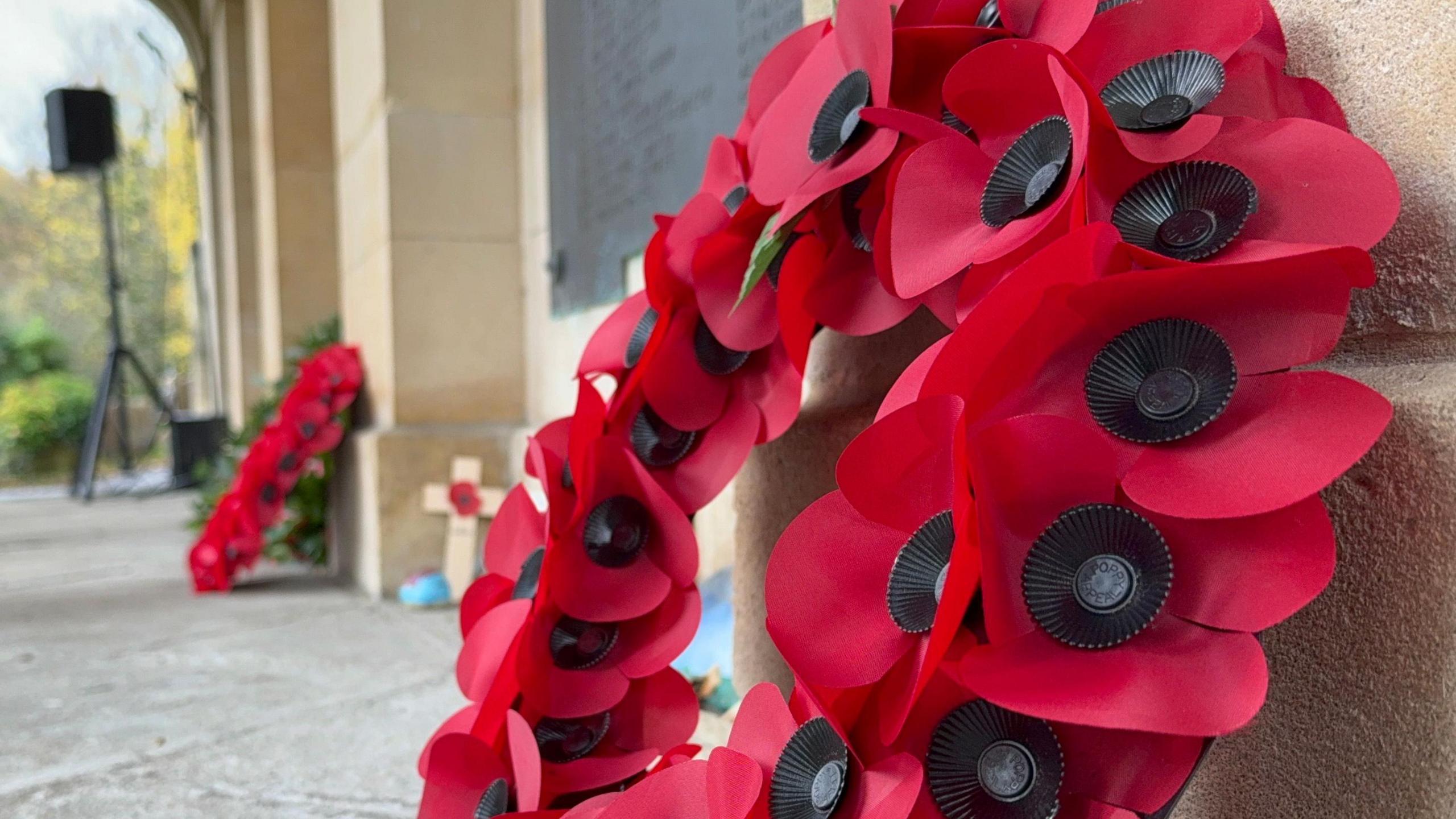A poppy wreath is propped up against a wall at Arnos Vale cemetary for Armistice Day. 