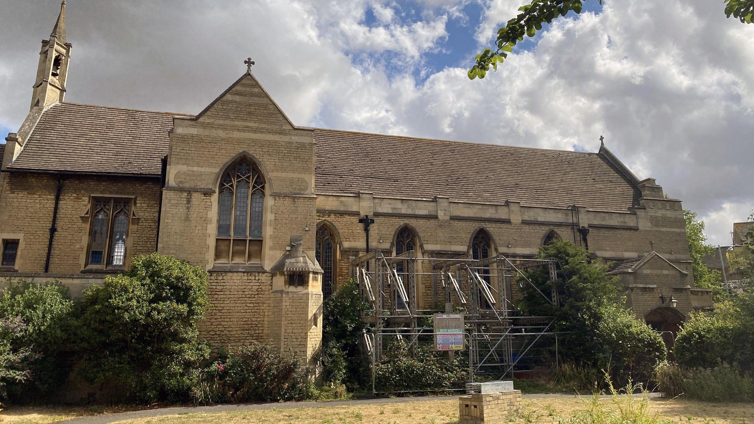 Exterior of the historic church building with scaffolding and bushes lining the building.