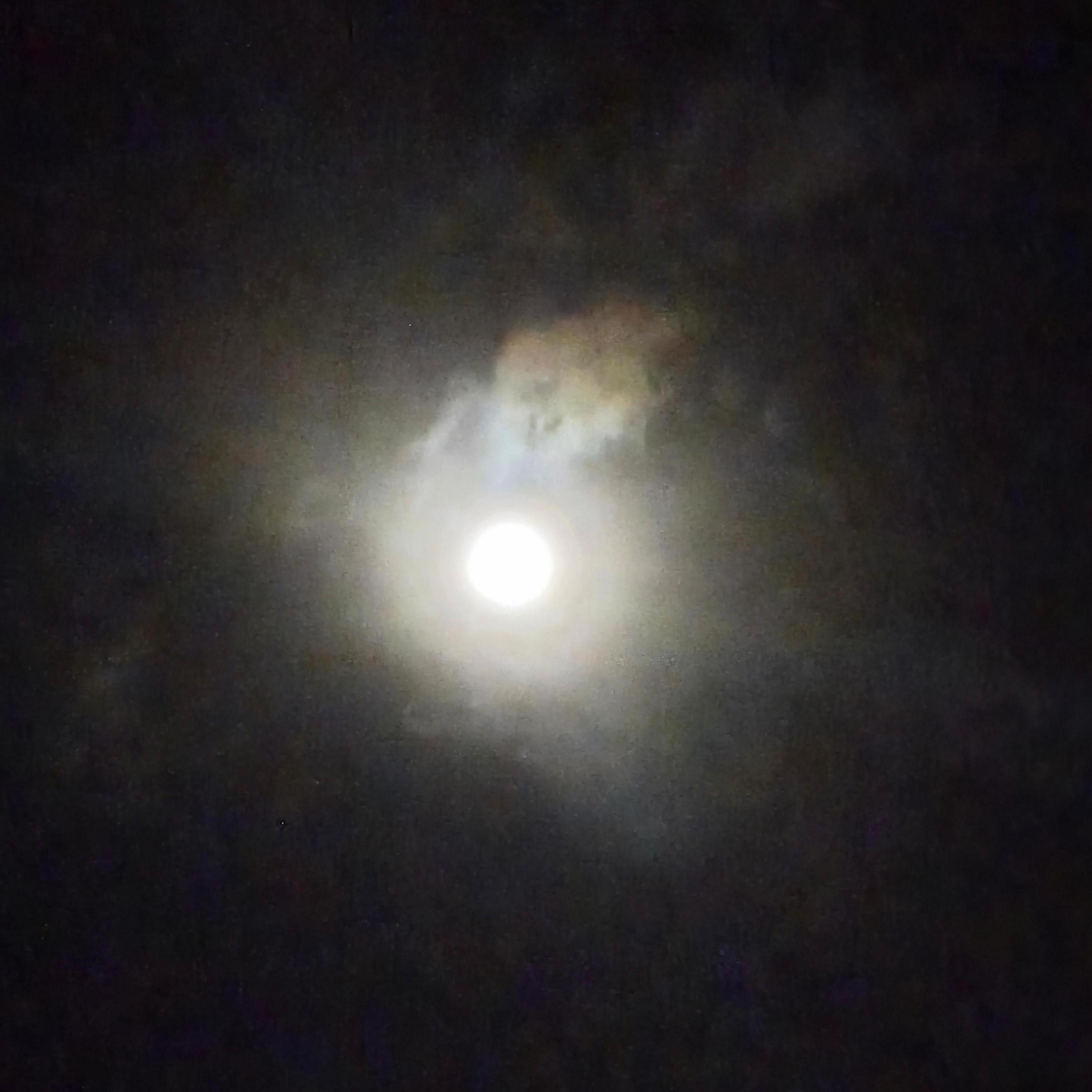 The full moon shining through clouds.